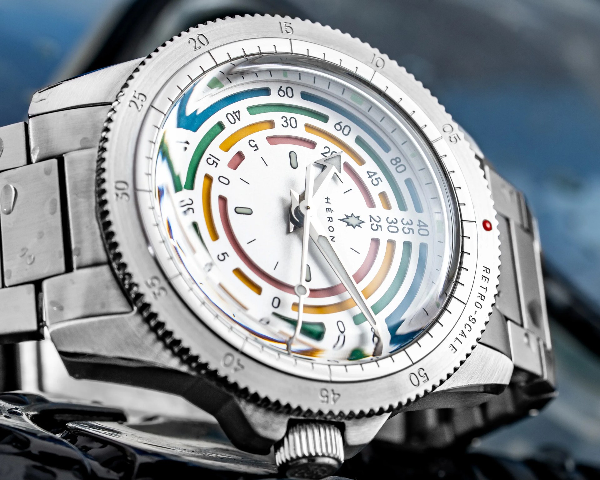 Close-up of a silver metal wristwatch with a colorful, multi-ring dial and a rotating bezel.