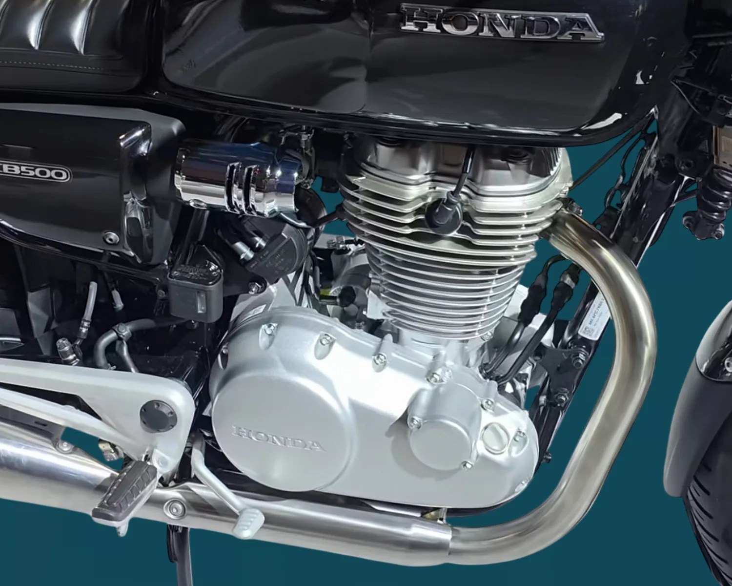 Close-up of a silver Honda motorcycle engine with black fuel tank and chrome exhaust pipe.