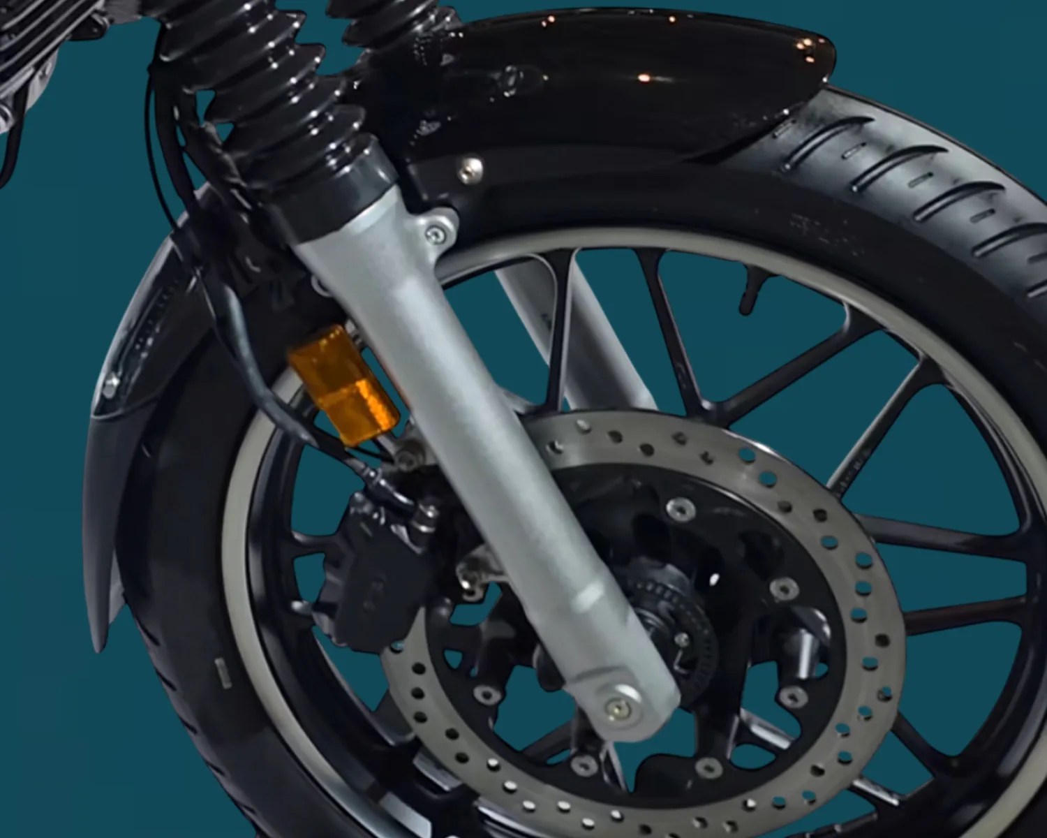 Close-up of a motorcycle front wheel with black tire, silver disc brake, black spokes, and silver suspension fork.