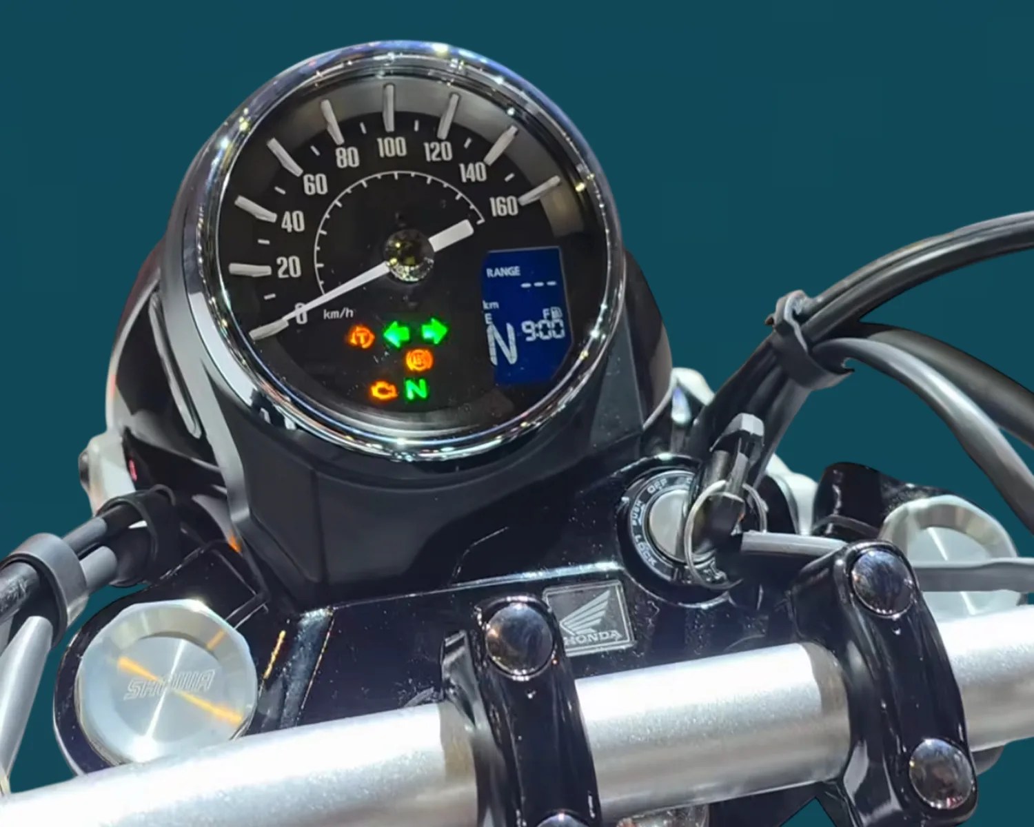 Close-up of a motorcycle speedometer with illuminated indicator lights and a Honda logo on the handlebar clamp.
