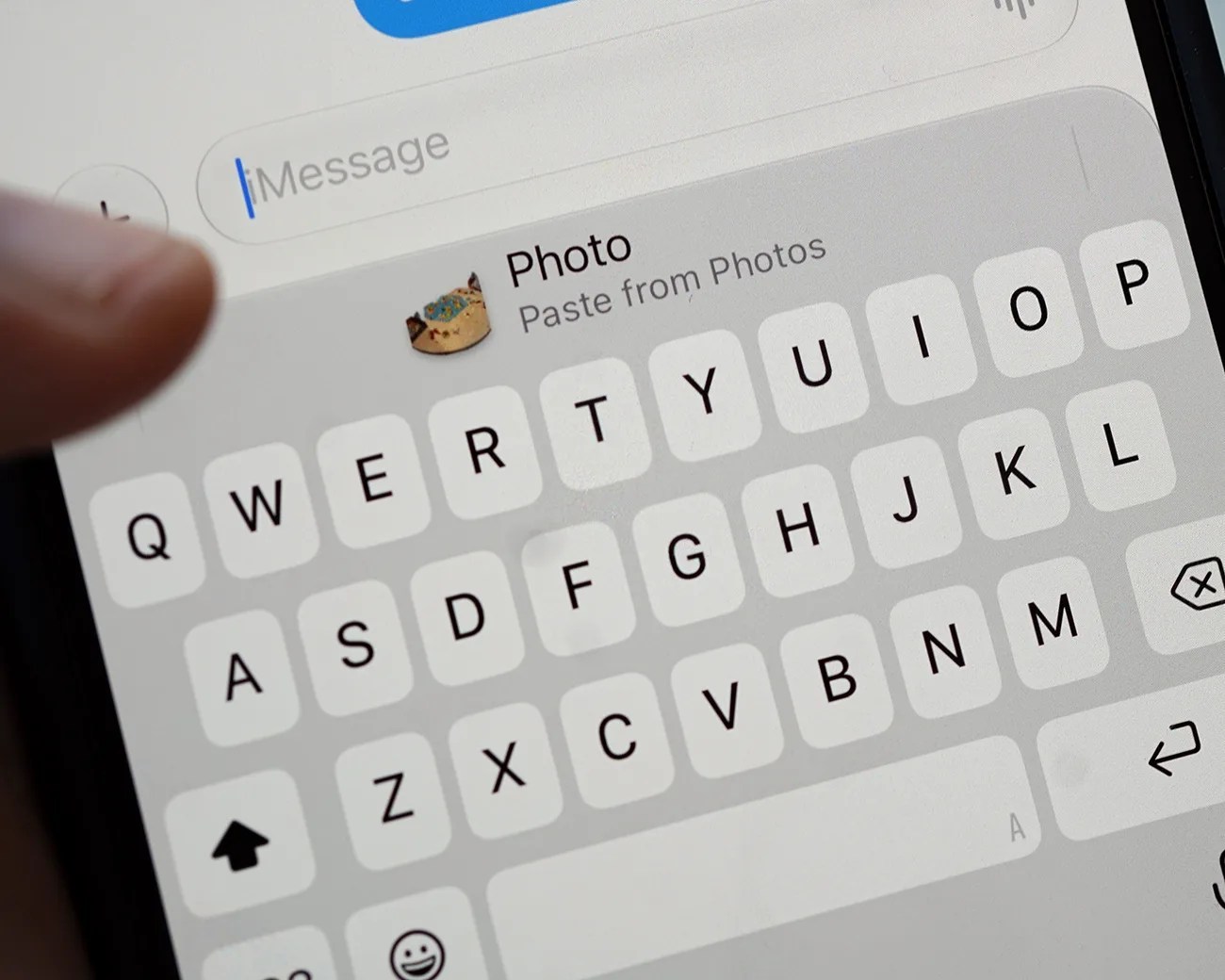 Close-up of a smartphone screen showing a keyboard and a "Photo Paste from Photos" option with a cat emoji above the keyboard.