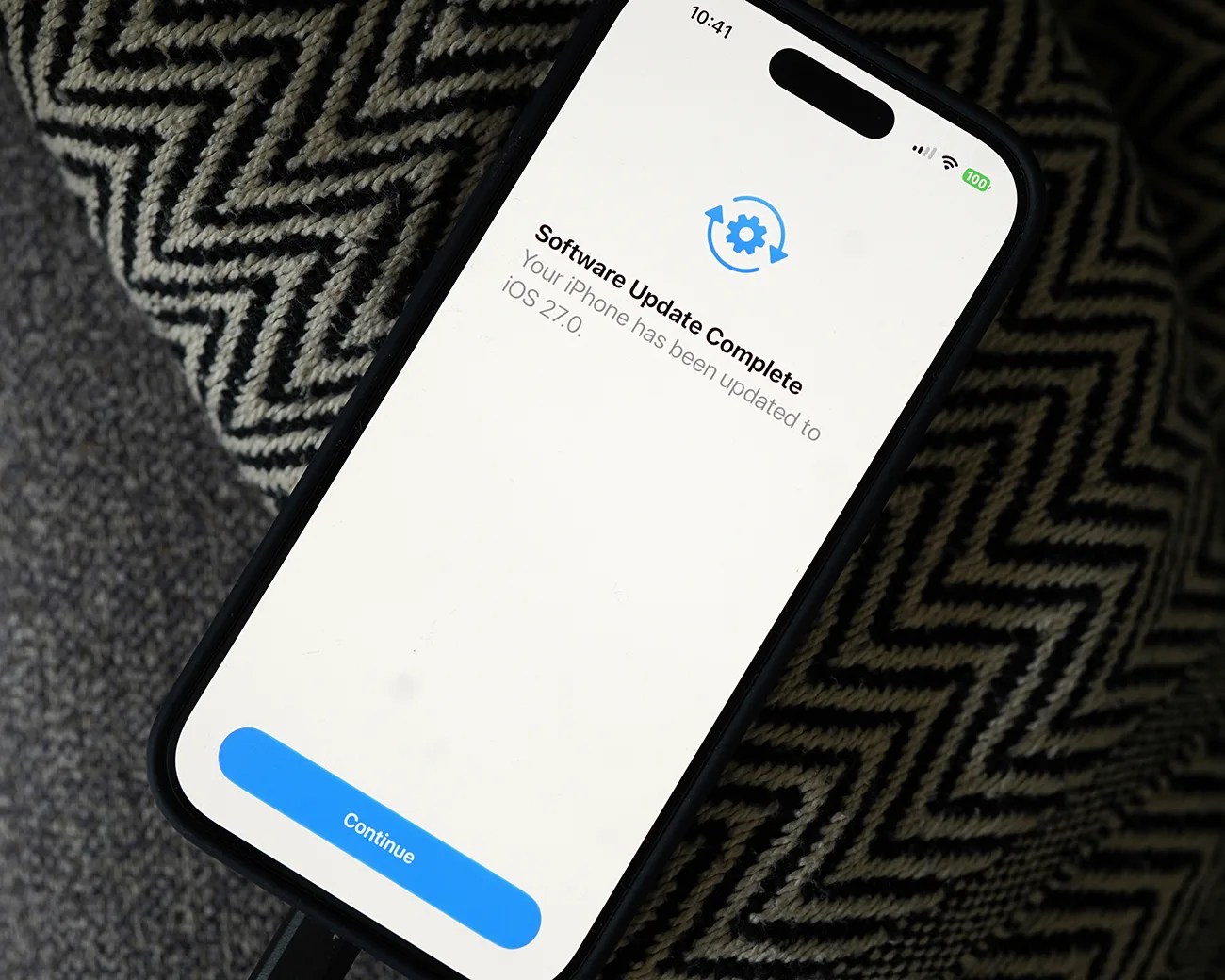 Smartphone screen showing "Software Update Complete" message for iOS 27.0 with a blue "Continue" button.
