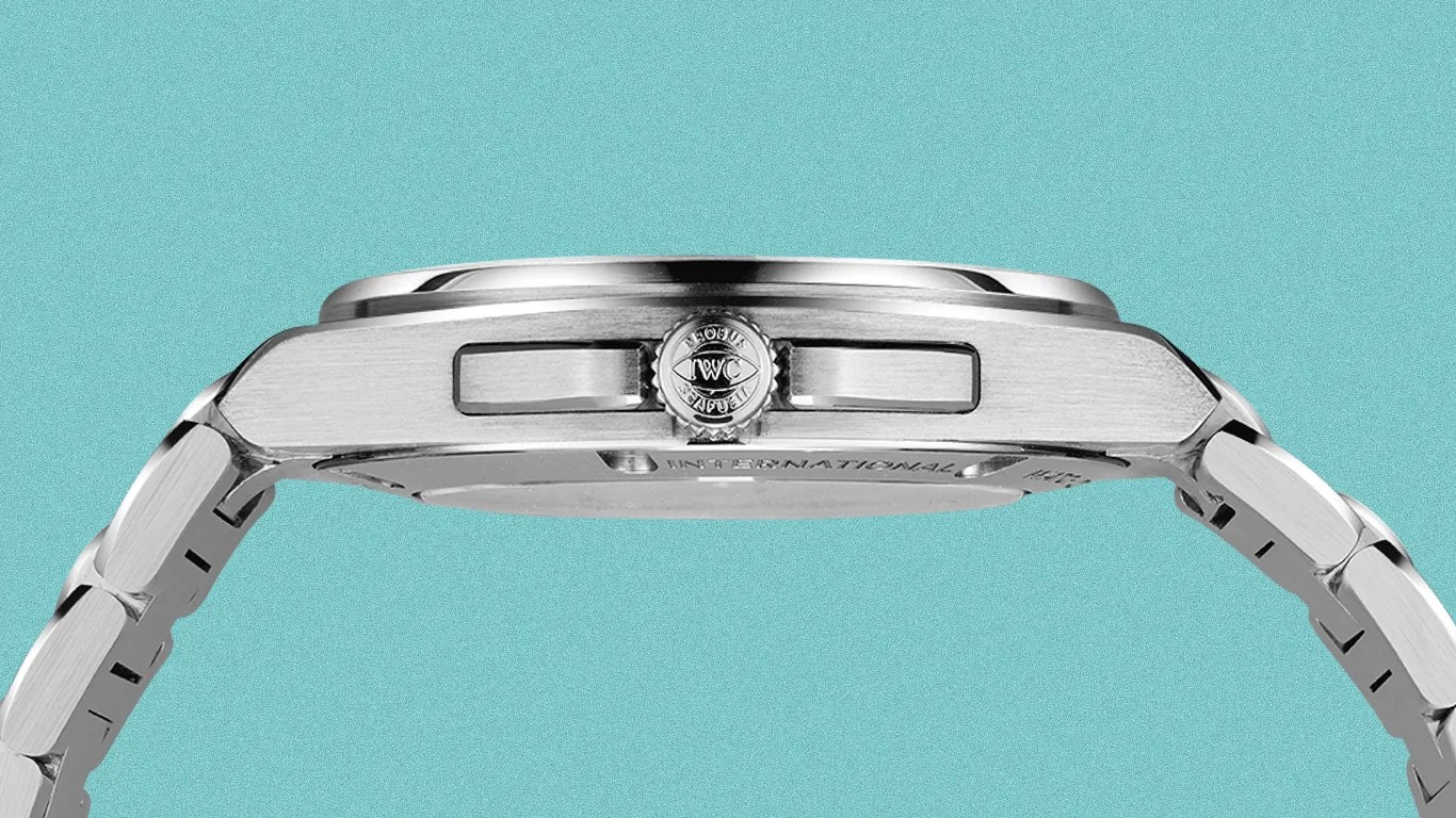 Side view of a silver stainless steel wristwatch with a crown engraved with "IWC" on a turquoise background.