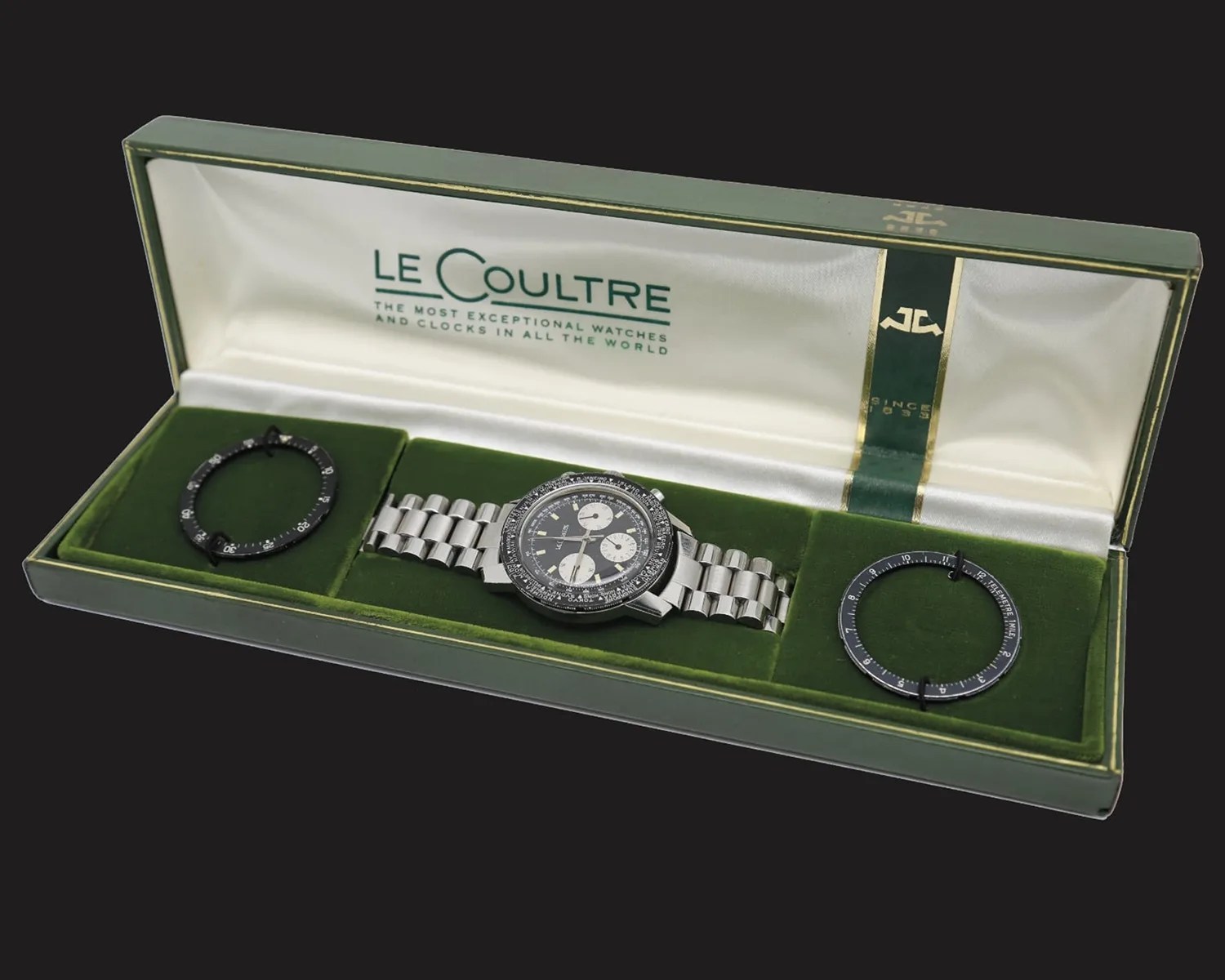 Silver metal LeCoultre chronograph wristwatch with black dial and three subdials in a green velvet-lined box with two black bezels.
