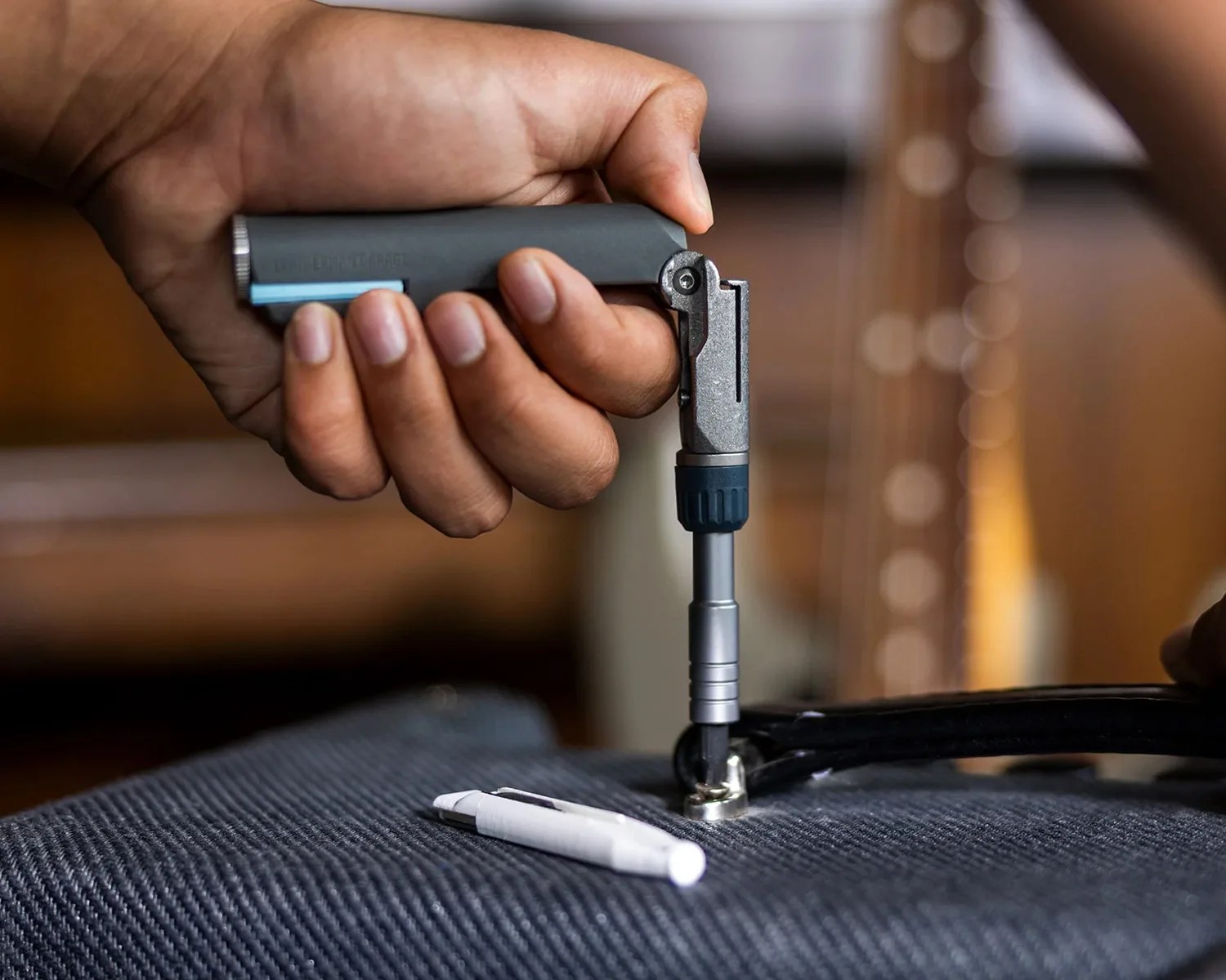 Hand holding a compact multi-tool screwdriver tightening a bolt on a black bicycle wheel.