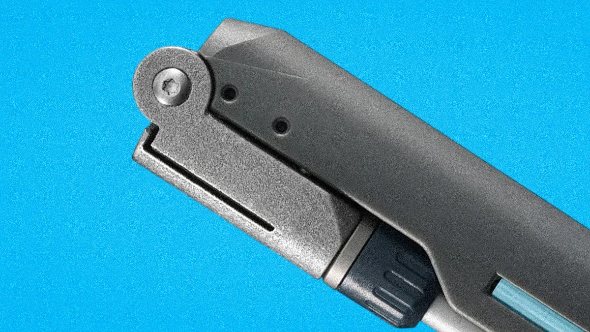 Close-up of a gray and black metal folding knife hinge against a blue background.