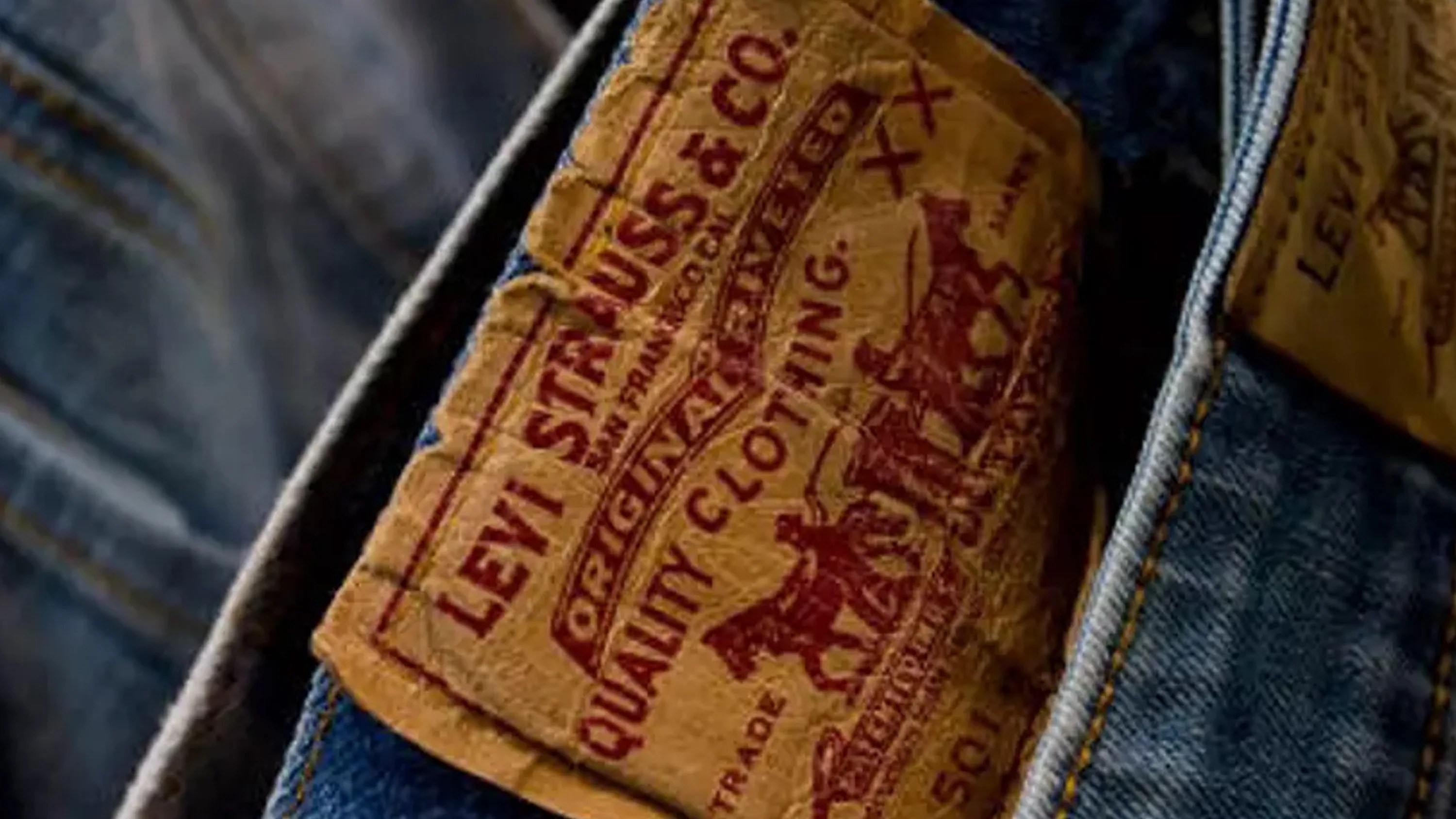 Close-up of a worn brown leather Levi Strauss & Co. patch on blue denim jeans.