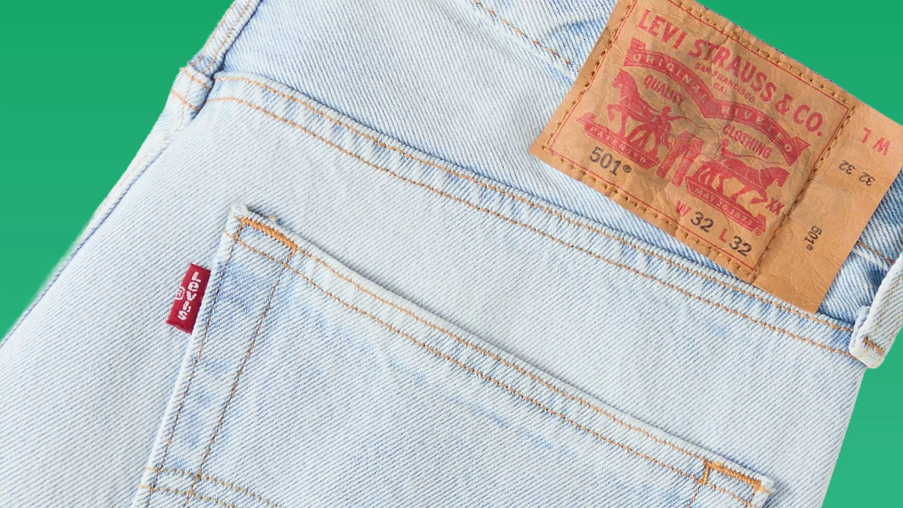 Light blue Levi's 501 jeans pocket with red Levi's tag and brown leather brand patch on green background.