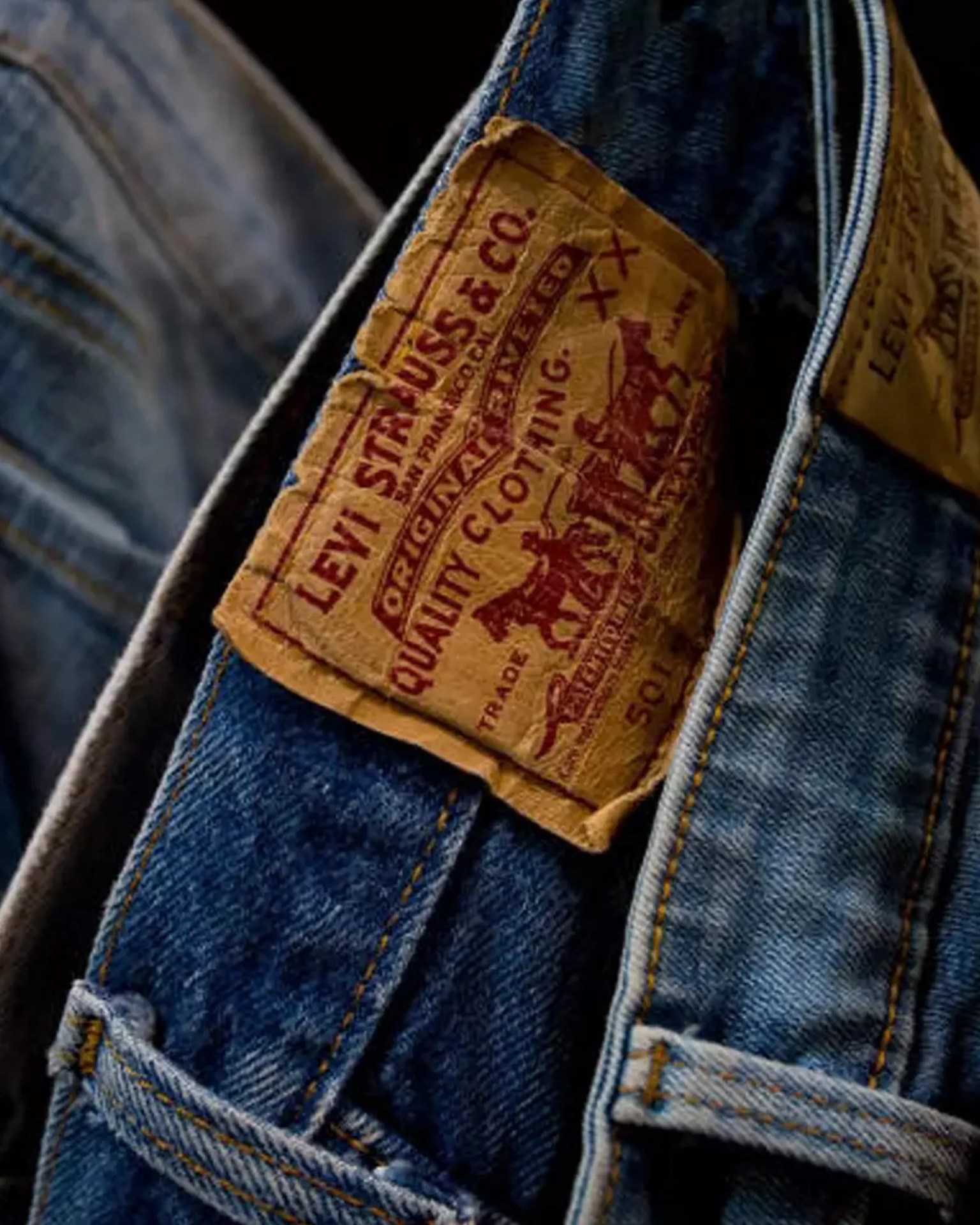Close-up of a worn brown leather Levi Strauss & Co. patch on blue denim jeans.