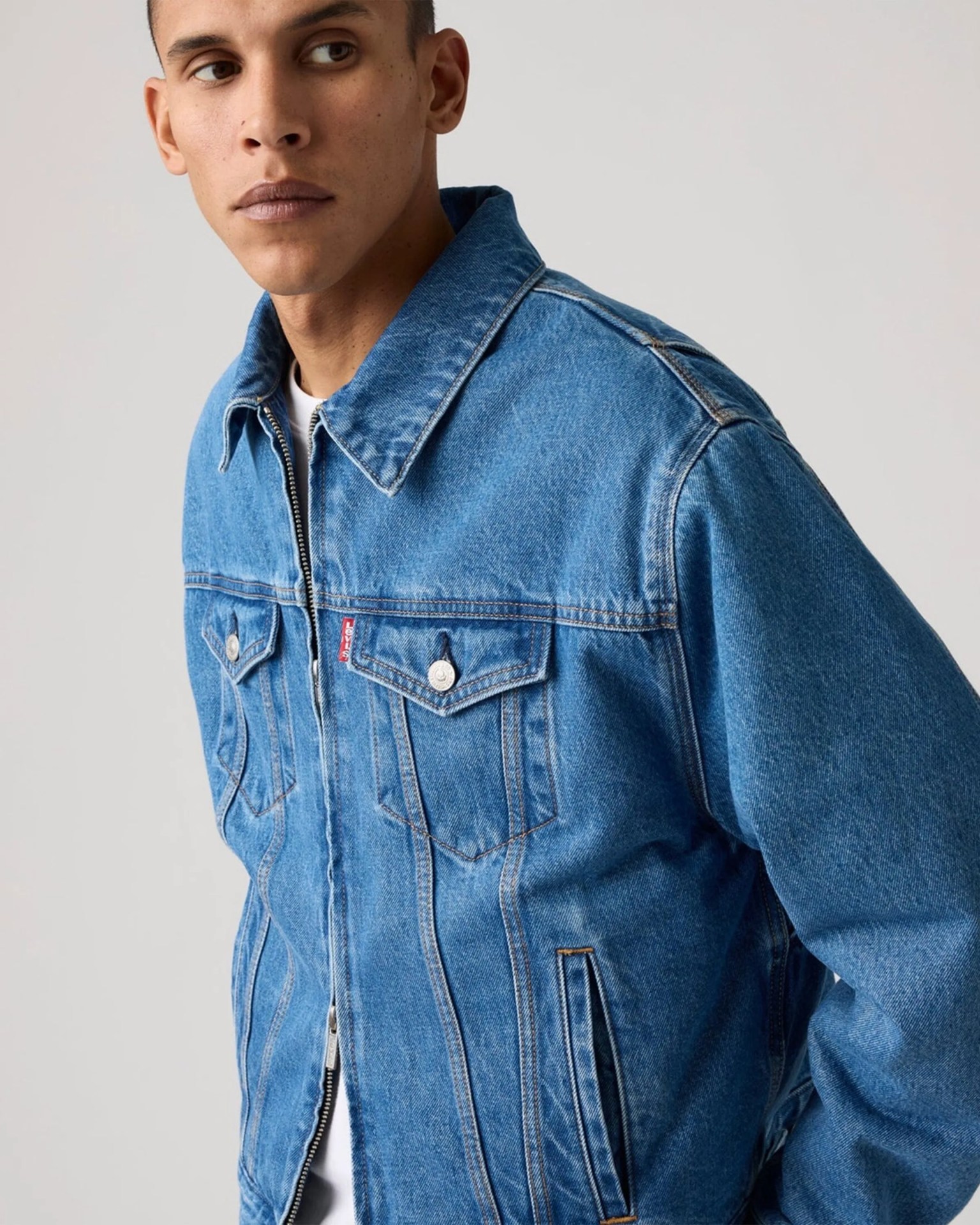 Man wearing a blue Levi's denim jacket with buttoned chest pockets and a zipper front.