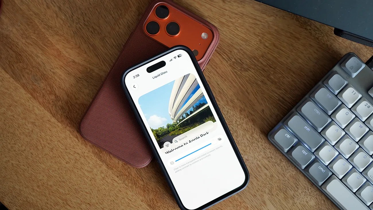 Two smartphones stacked on a wooden surface next to a gray mechanical keyboard, one phone displaying an app with a building image.