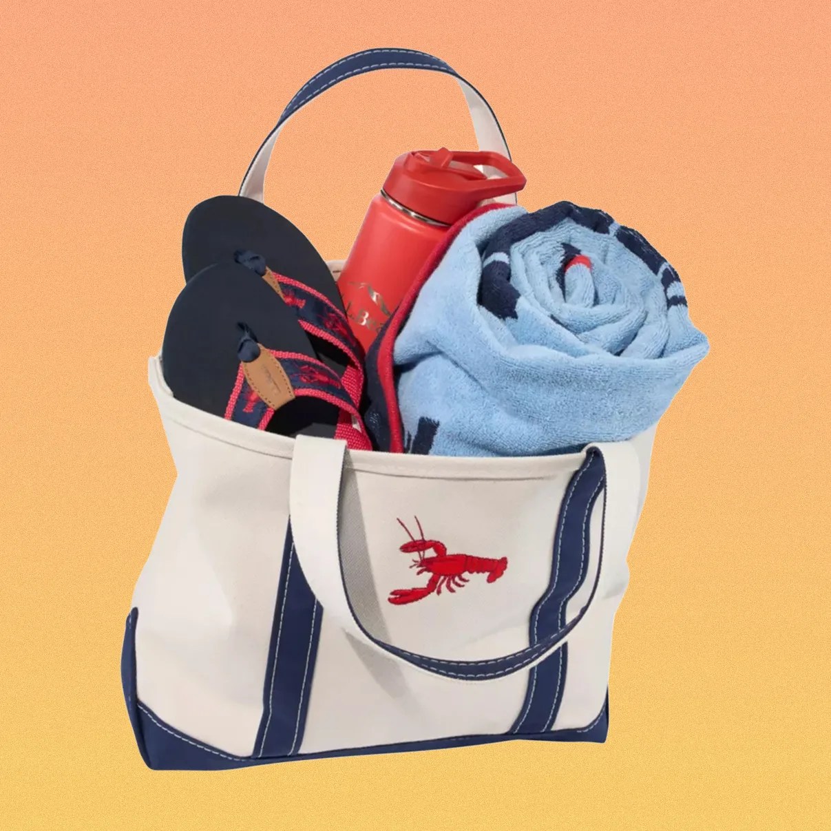 Canvas tote bag with navy trim and red lobster embroidery, containing navy flip-flops, a red water bottle, and a rolled blue towel.