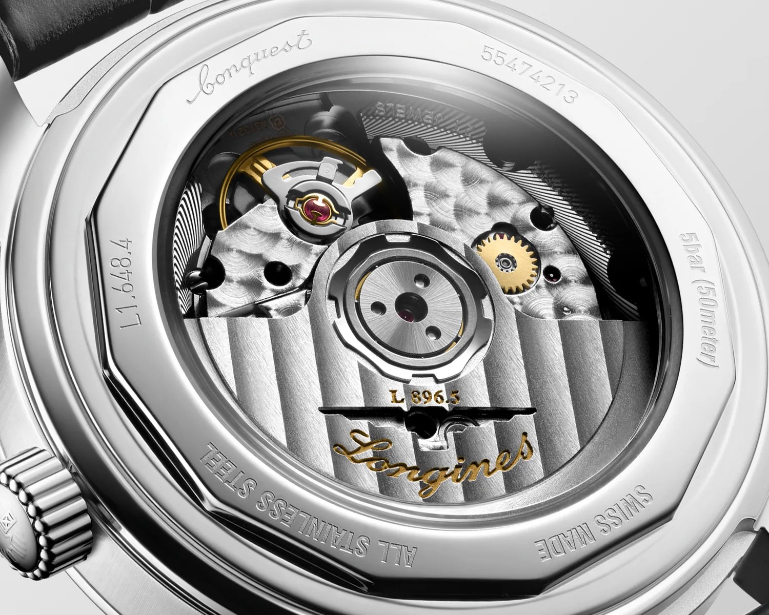 Close-up of Longines watch movement with visible gears and engraved text on stainless steel case back.