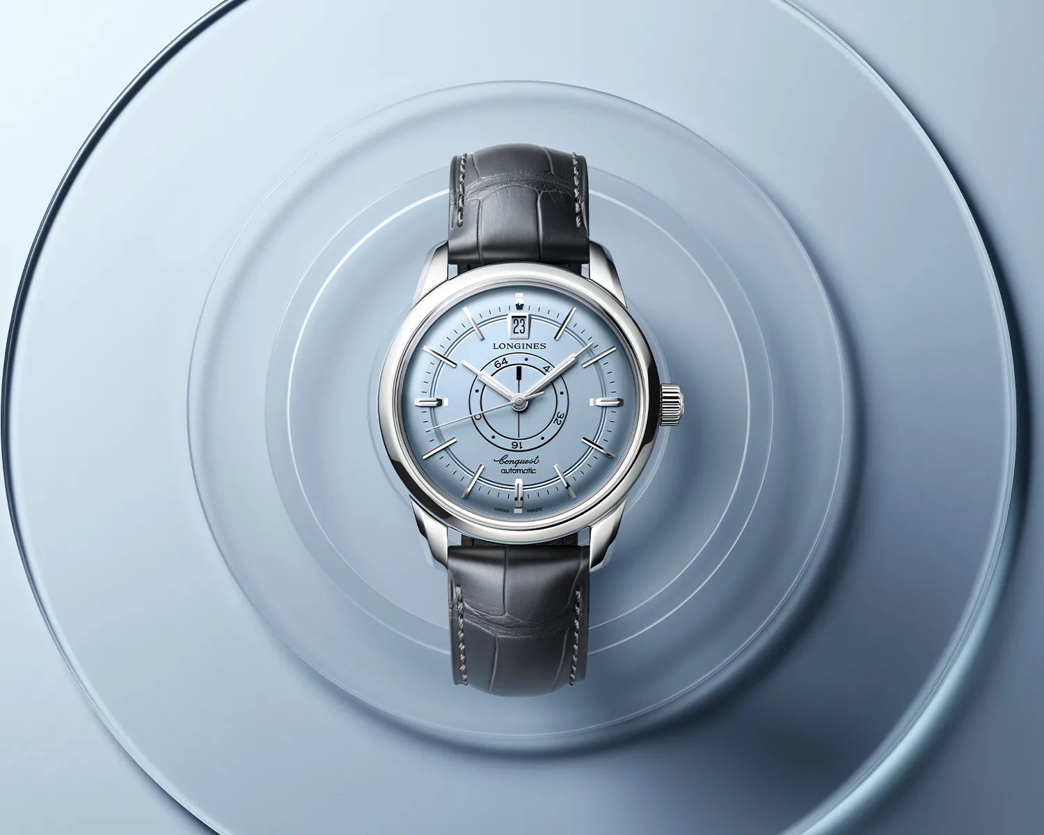 Silver Longines Conquest automatic watch with light blue dial and black leather strap on concentric blue plates.