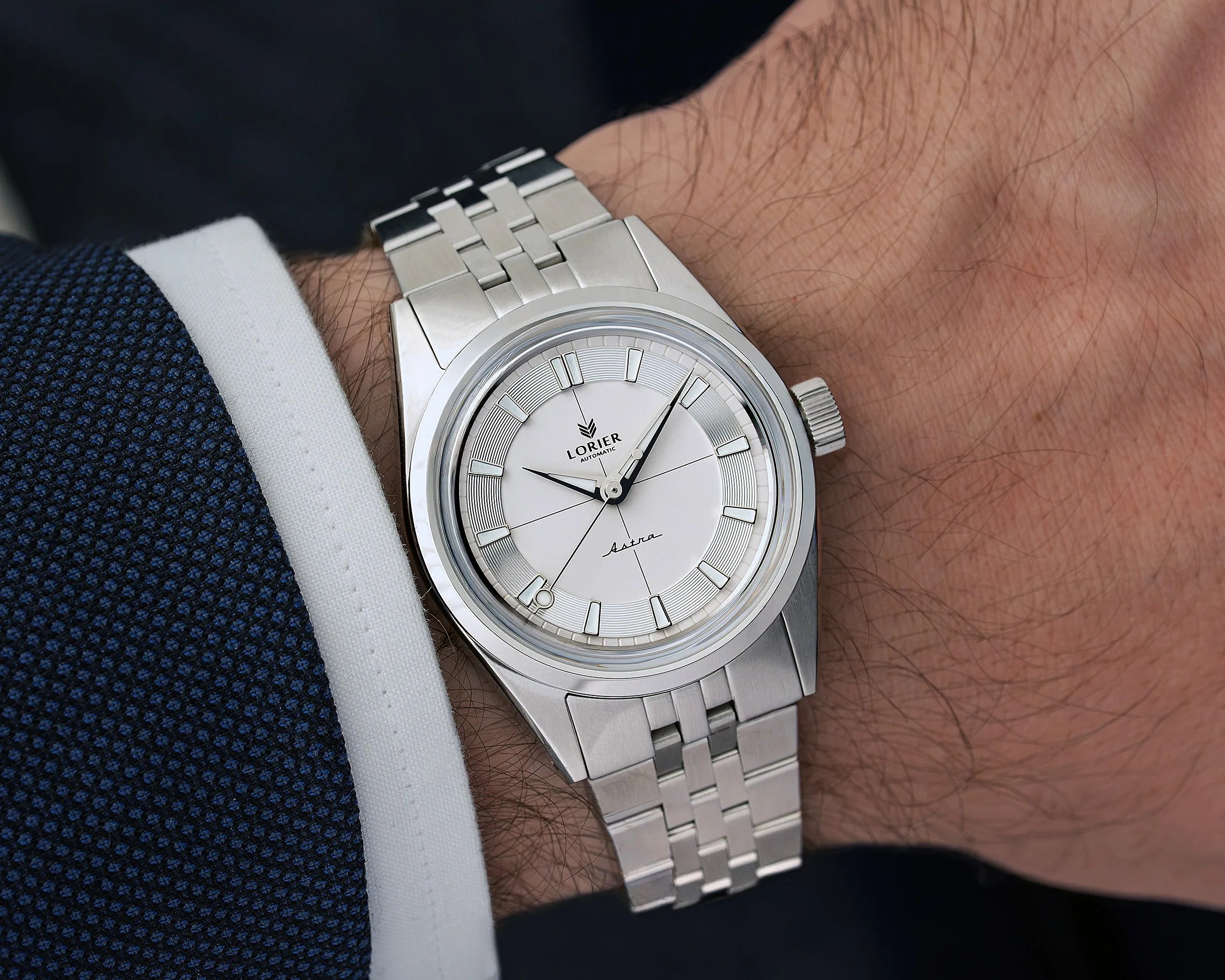 Silver Lorier Astra automatic wristwatch with white dial and metal bracelet on a wrist.