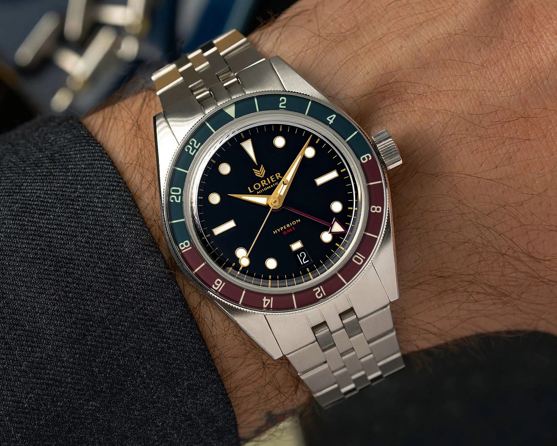 Stainless steel Lorier Hyperion GMT wristwatch with black dial and red-blue bezel on a wrist.