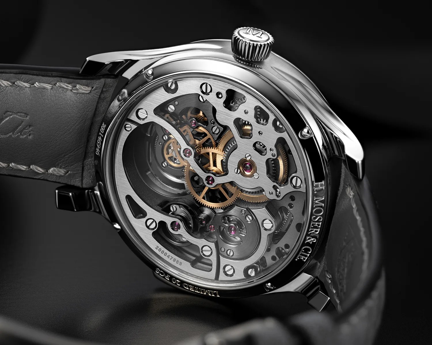 Close-up of a mechanical watch movement with visible gears and screws inside a polished metal case, attached to a black leather strap.