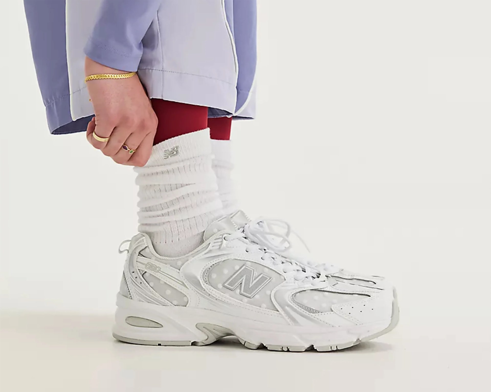 White New Balance sneakers with polka dot pattern worn with scrunched white socks and red leggings.