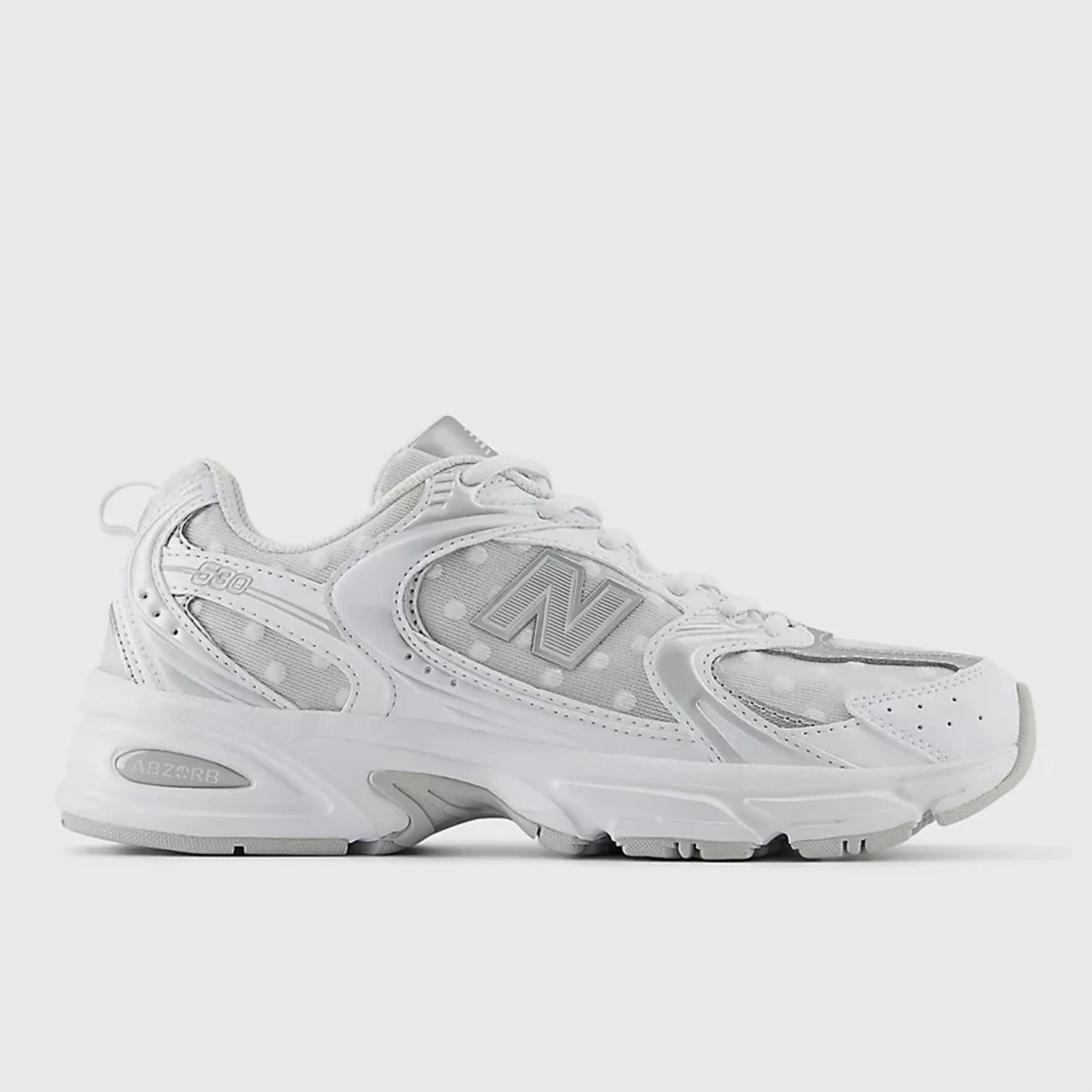White New Balance 530 sneaker with mesh and leather upper featuring polka dot pattern and ABZORB cushioning sole.