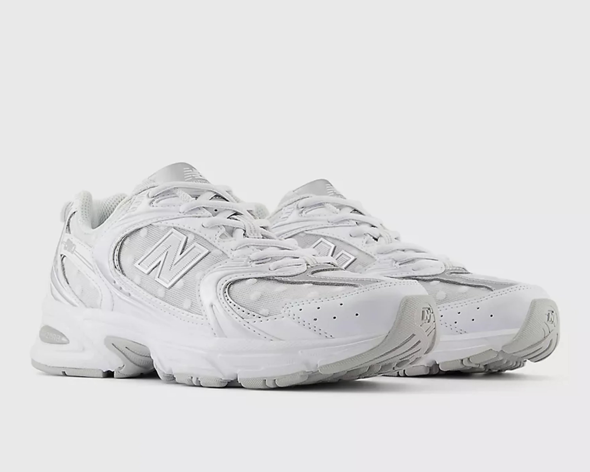 Pair of white New Balance running shoes with mesh and leather details on a white background.