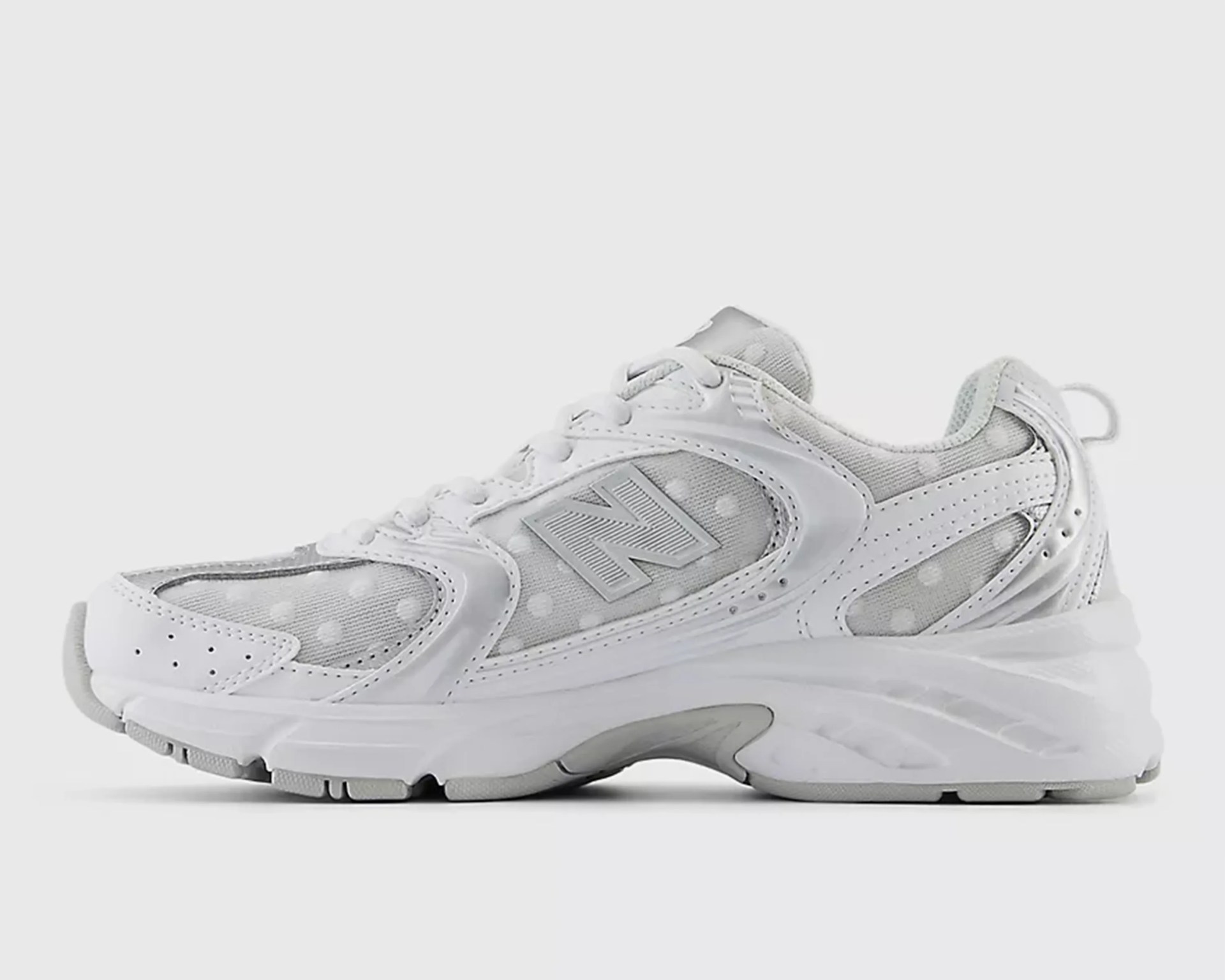 White and gray New Balance sneaker with mesh panels featuring polka dots and a chunky sole.