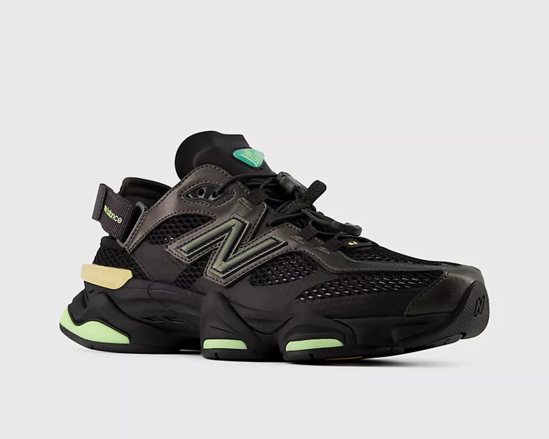Black and dark gray New Balance sneaker with mesh panels and light green accents on sole and logo.