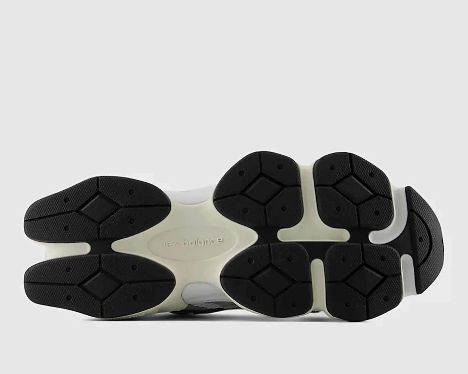 White and black New Balance sneaker sole with textured black rubber grips.