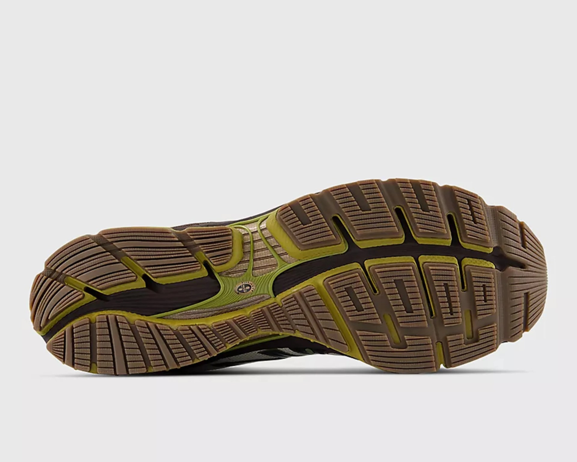 Brown and green rubber shoe sole with deep grooves and tread pattern.