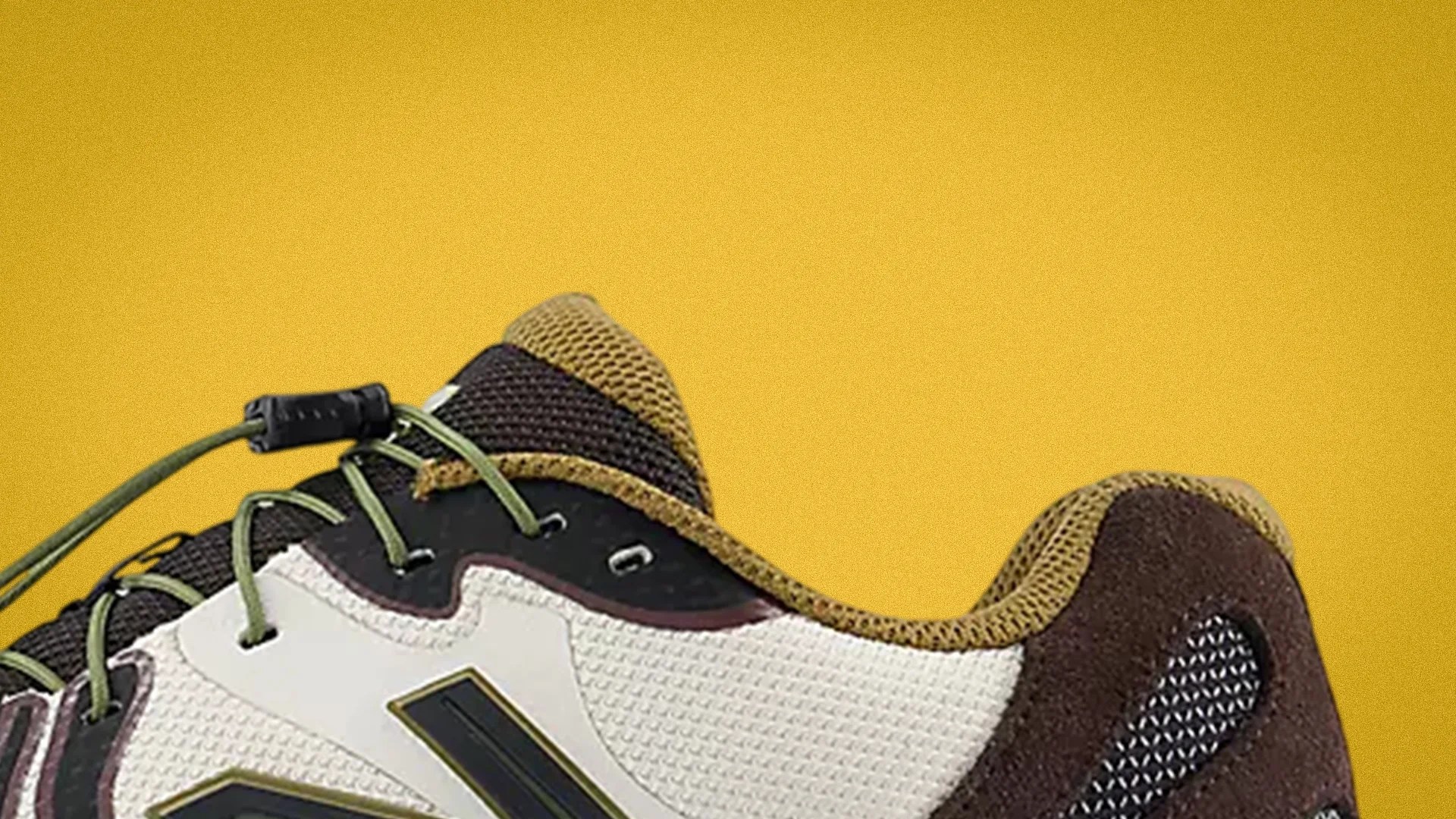 Close-up of a sneaker with beige mesh, black and brown suede, olive green laces, and a yellow background.