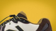 Close-up of a sneaker with beige mesh, black and brown suede, olive green laces, and a yellow background.