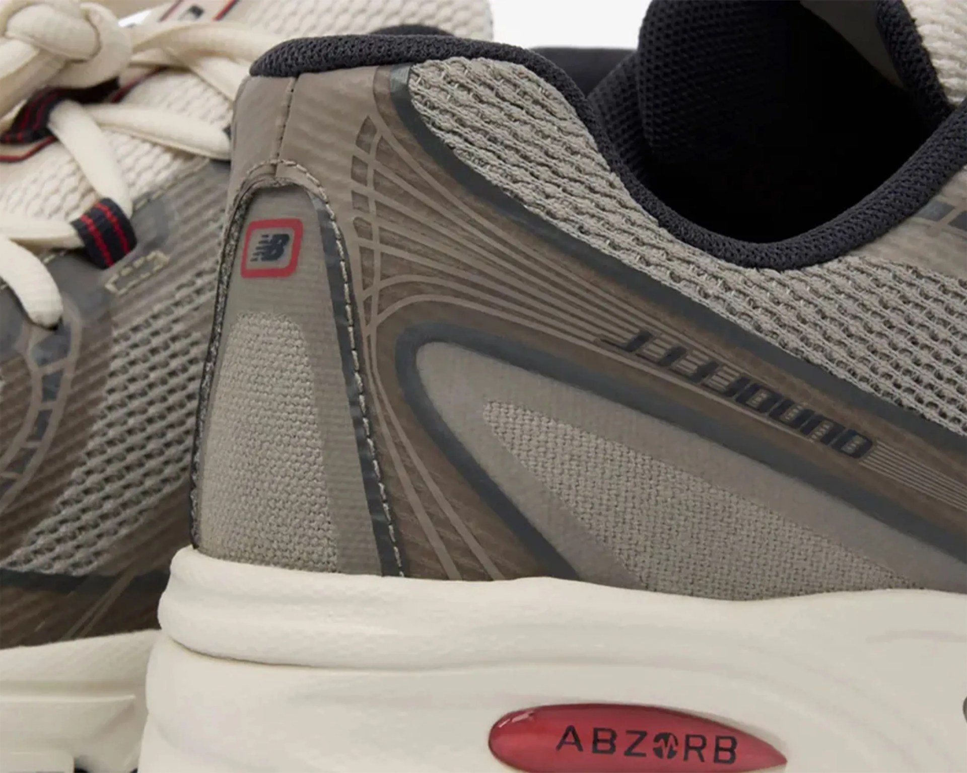 Close-up of beige and gray New Balance running shoes with ABZORB cushioning visible on the white sole.