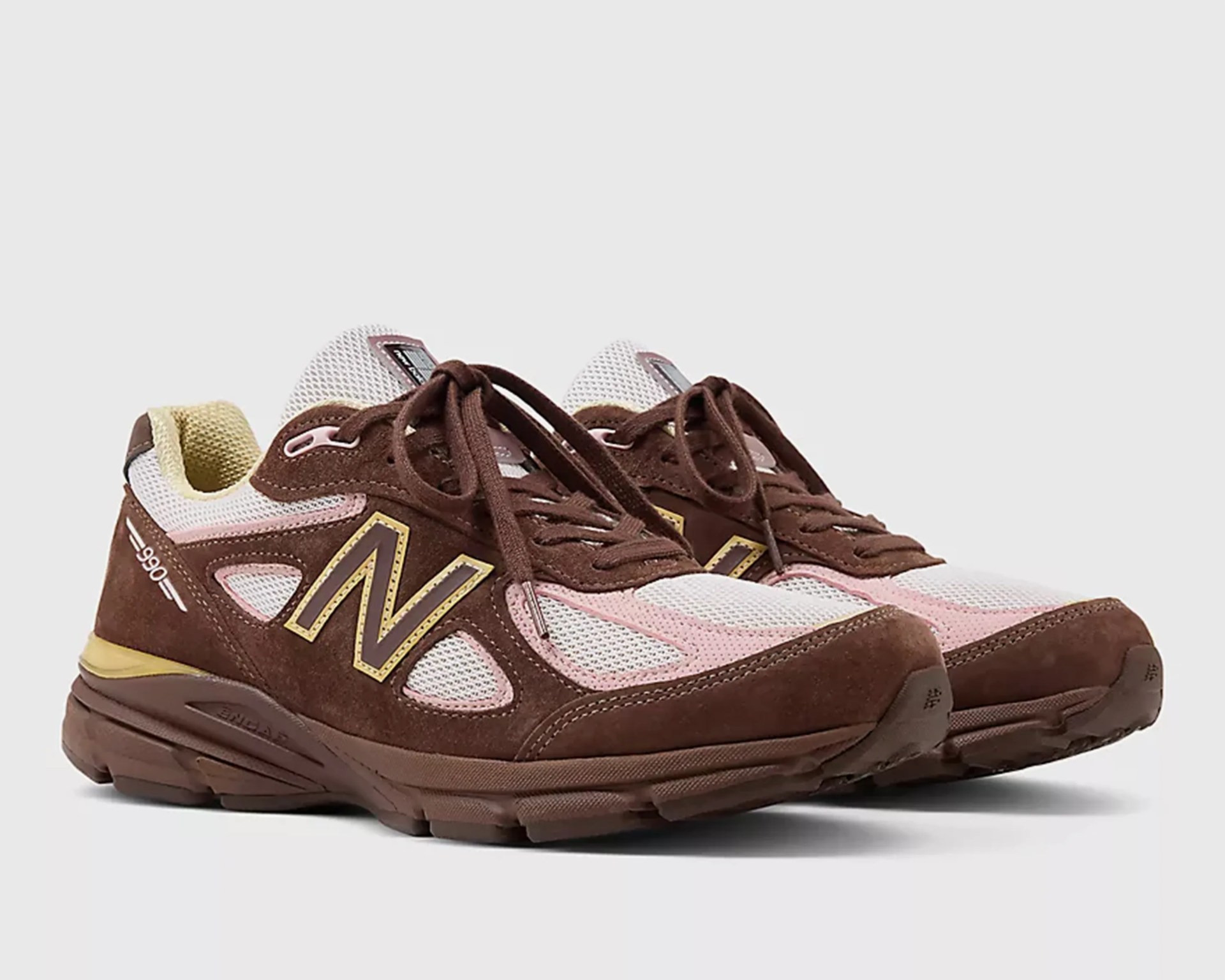 Brown and pink New Balance 990 sneakers with mesh panels and yellow accents.