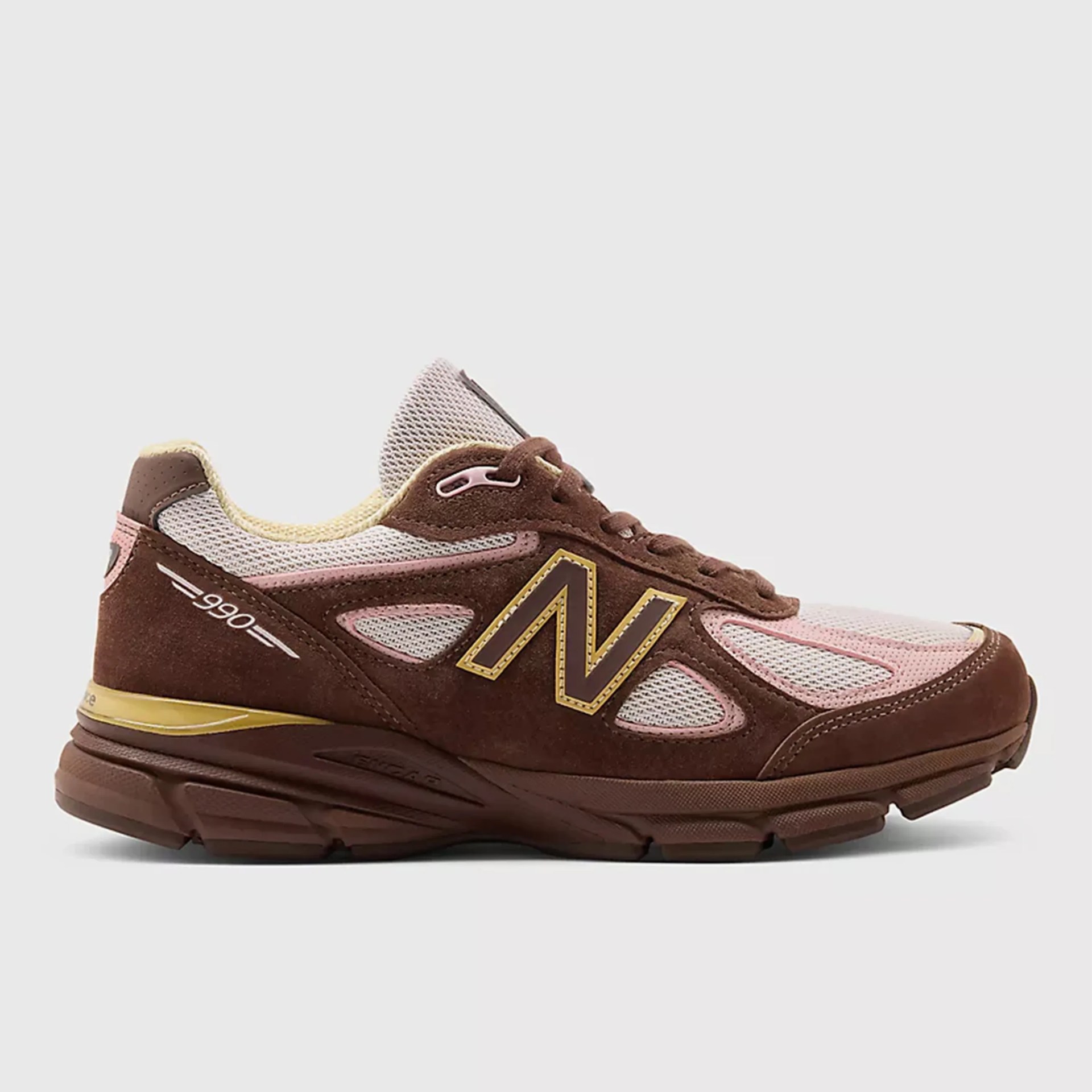 Brown and pink New Balance 990 sneakers with mesh and suede upper and yellow accents.