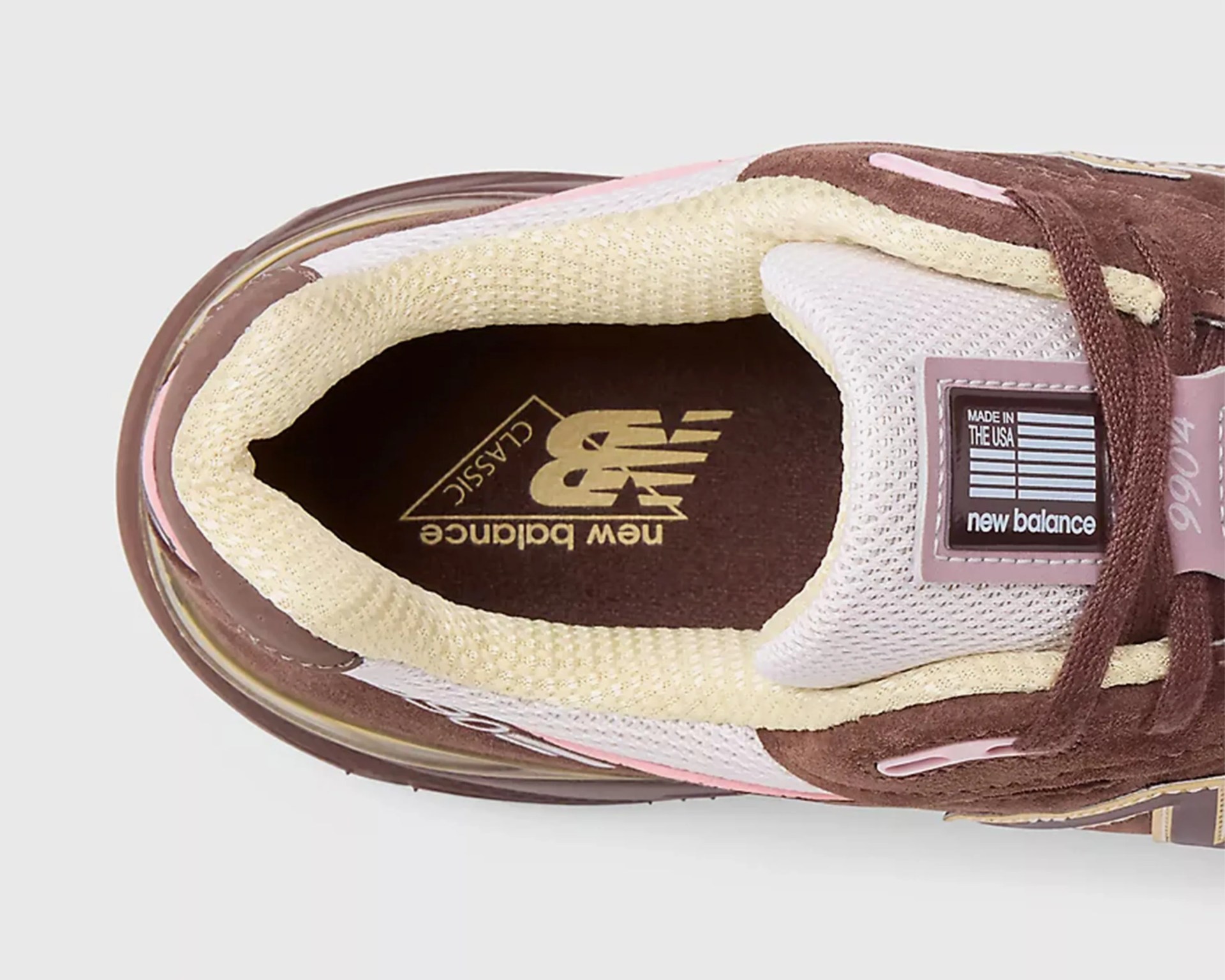 Top view of a brown and beige New Balance 990v4 sneaker showing the padded collar, mesh tongue, and insole with logo.