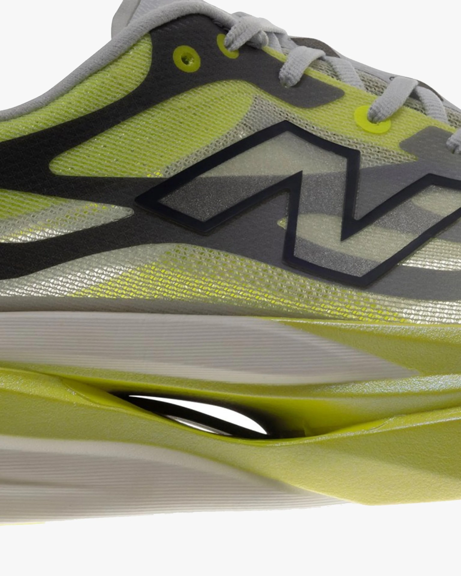 Close-up of a yellow and gray New Balance sneaker with a black "N" logo and white laces.