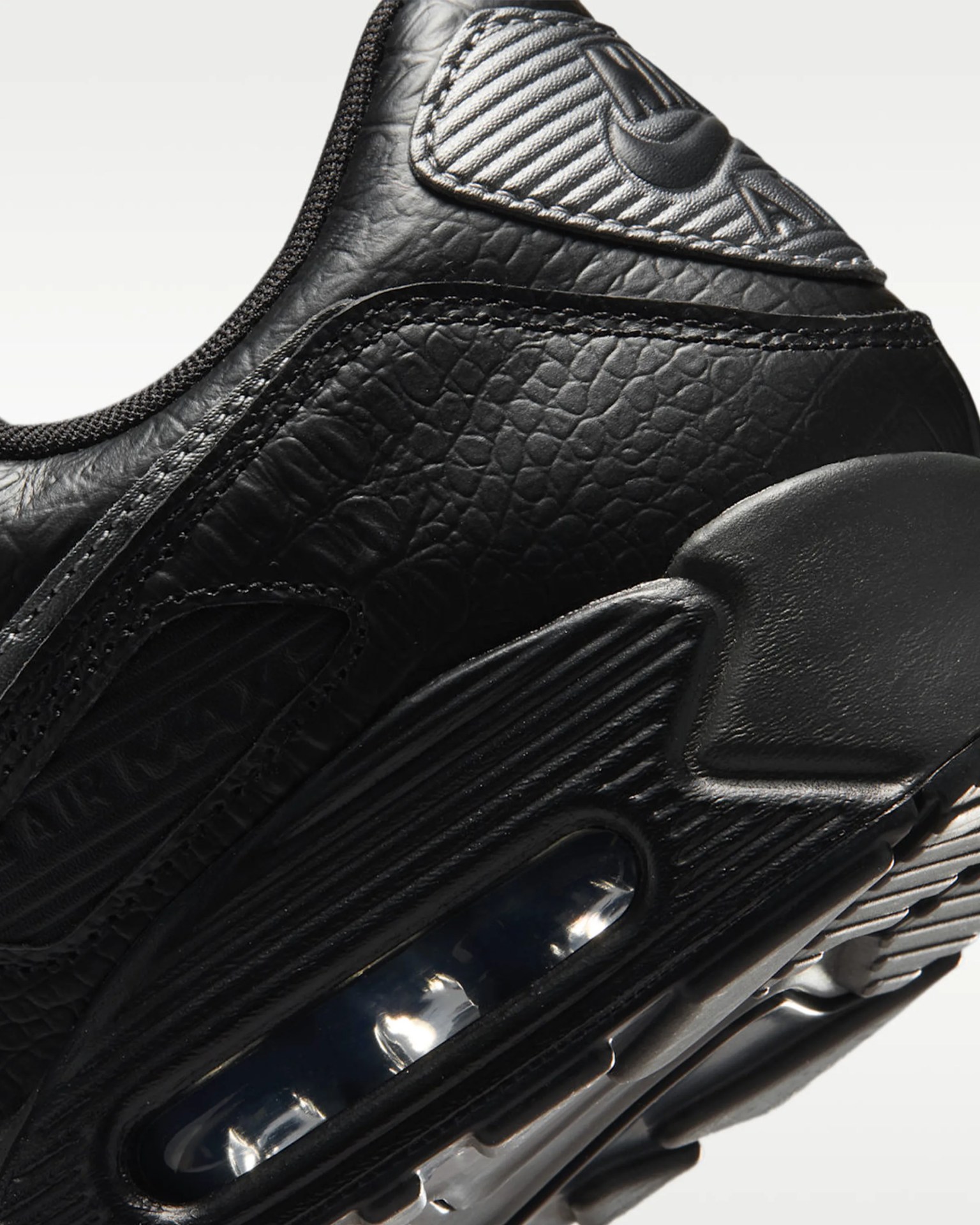 Close-up of black textured leather sneaker heel with visible air cushioning and stitched detailing.
