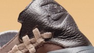 Close-up of a brown leather sneaker tongue with embossed Nike logo and beige woven laces.