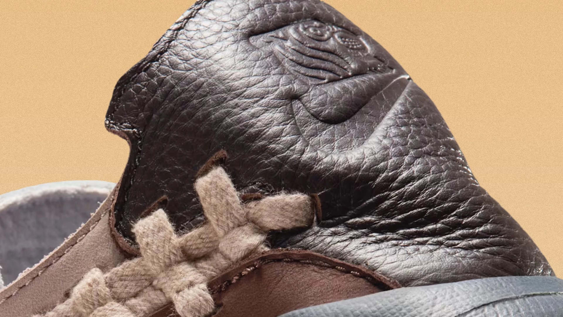 Close-up of a brown leather sneaker tongue with embossed Nike logo and beige woven laces.