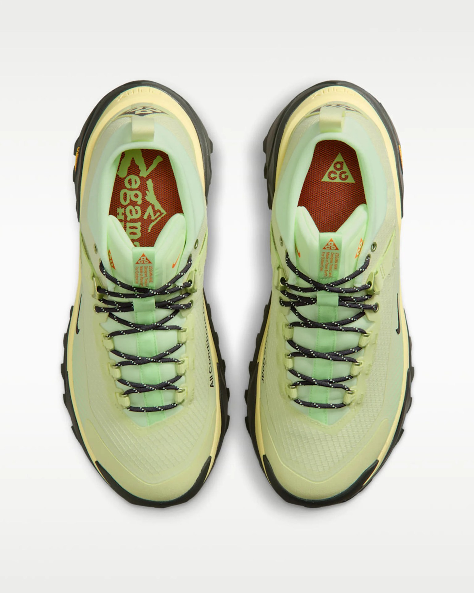 Pair of light green Nike ACG sneakers with black and white laces and orange insoles viewed from above.