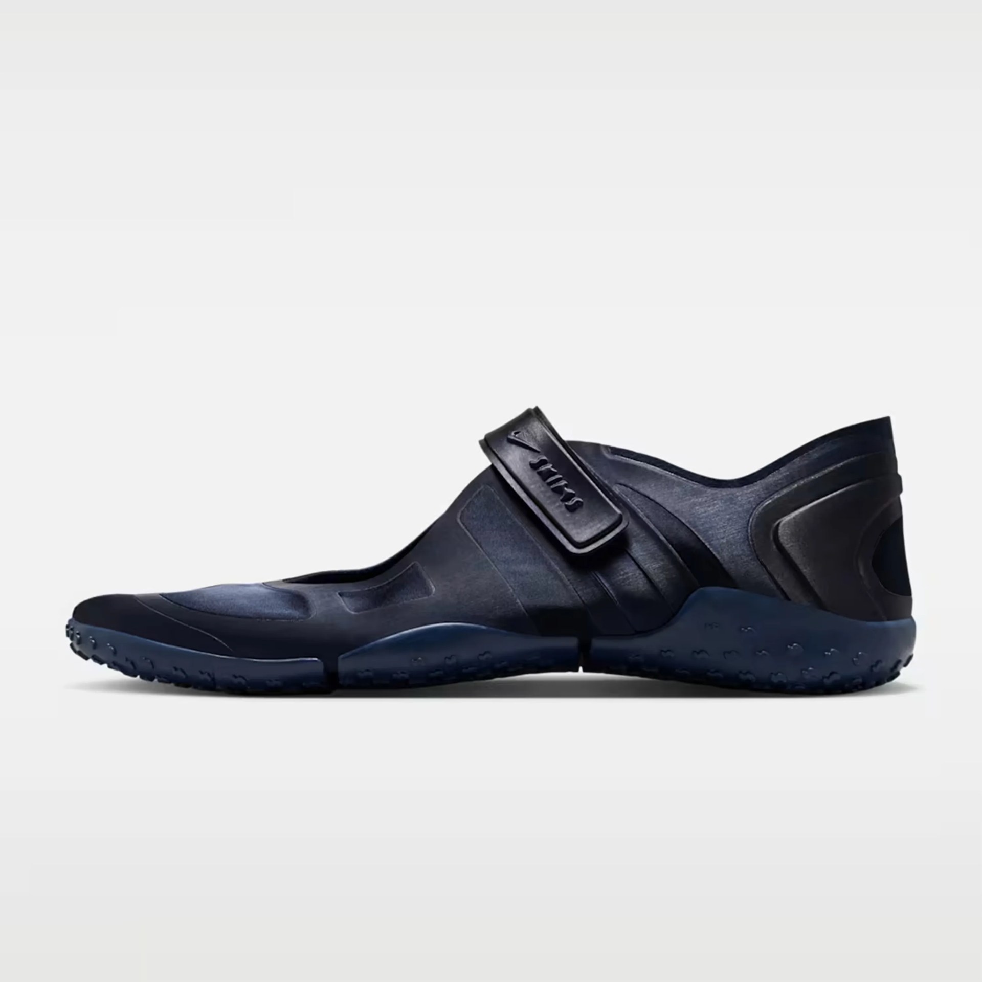 Black slip-on shoe with adjustable strap and textured sole on a white background.