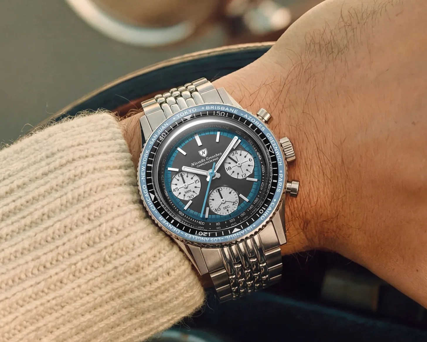 Silver Nivada Grenchen Chronoking wristwatch with black and blue dial and three subdials on a metal bracelet.