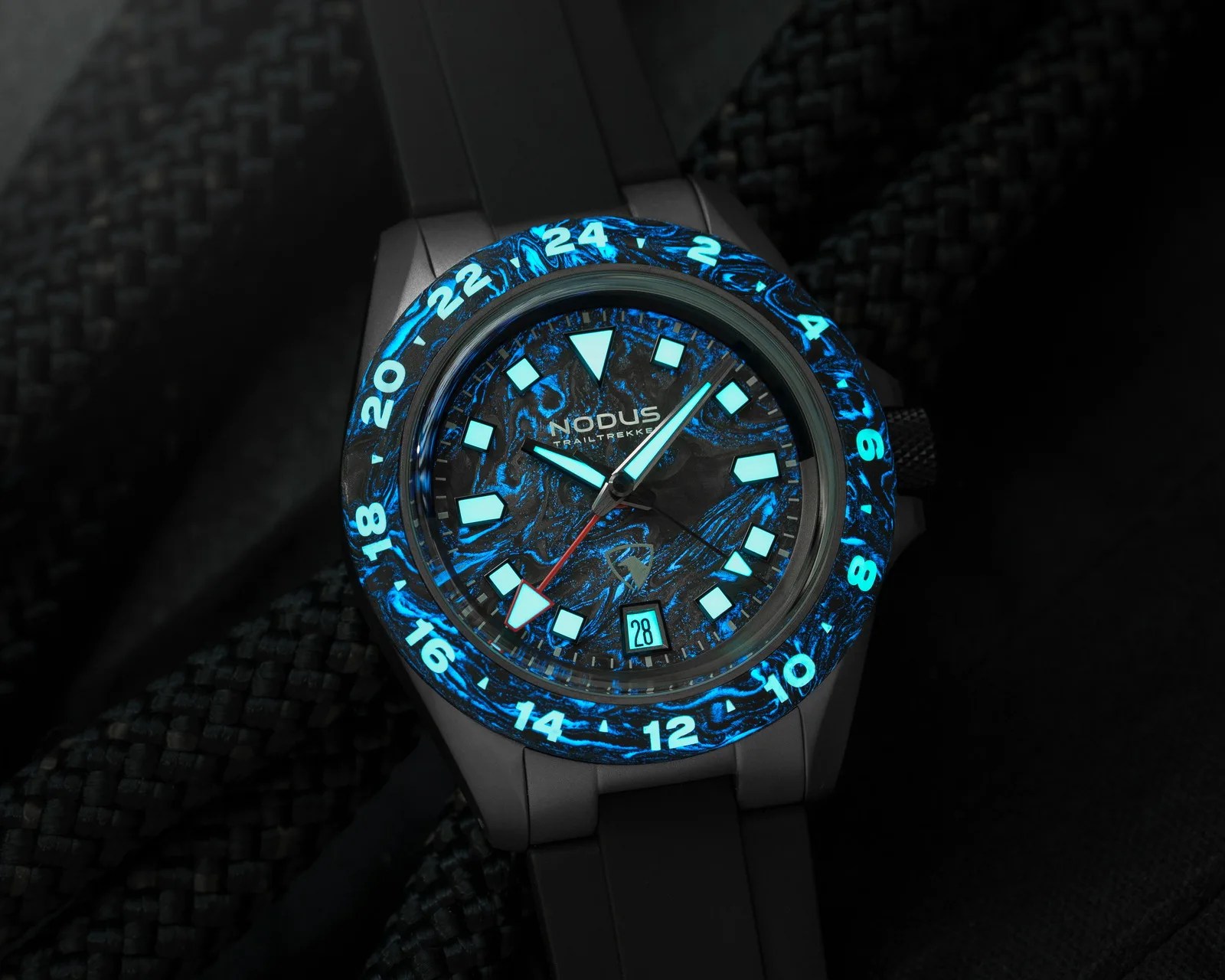 Black Nodus wristwatch with glowing blue hour markers and bezel numbers, black strap, and date display at 6 o'clock.