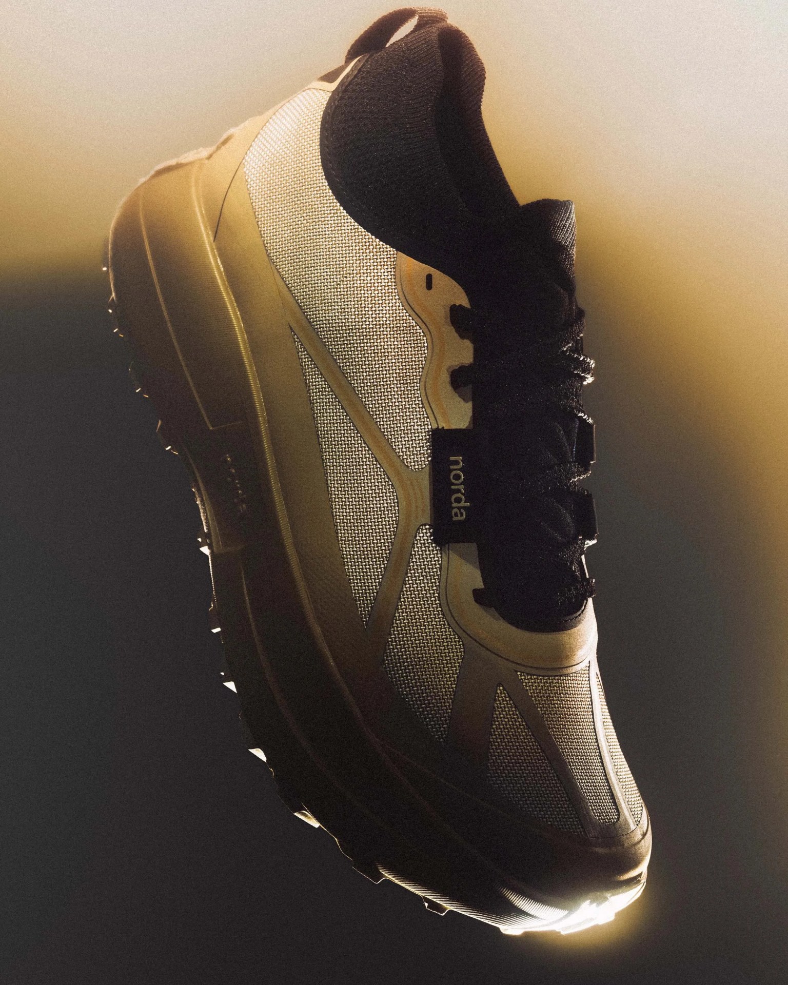 Beige and black athletic shoe with mesh fabric and thick sole, labeled "norda" on the side.