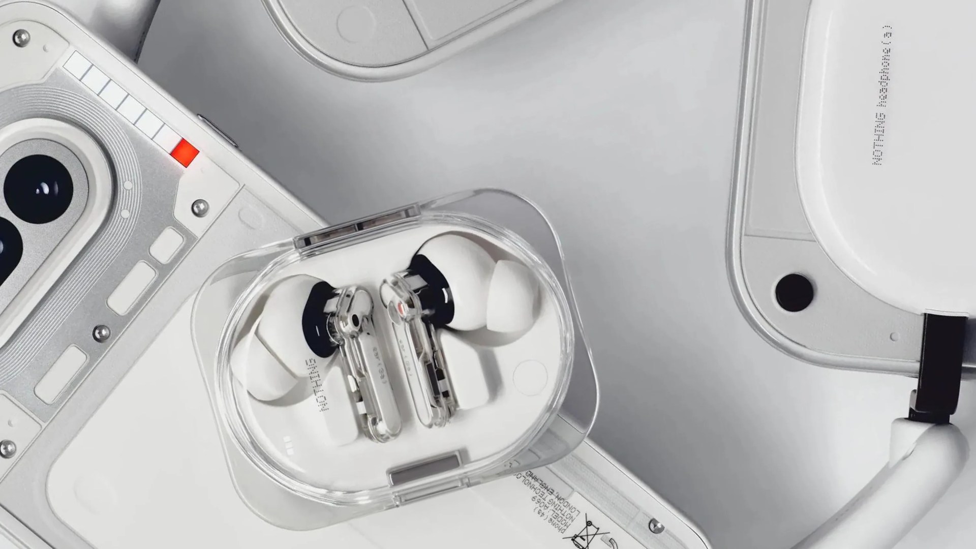 Transparent charging case with white wireless earbuds on a white tech device surface.