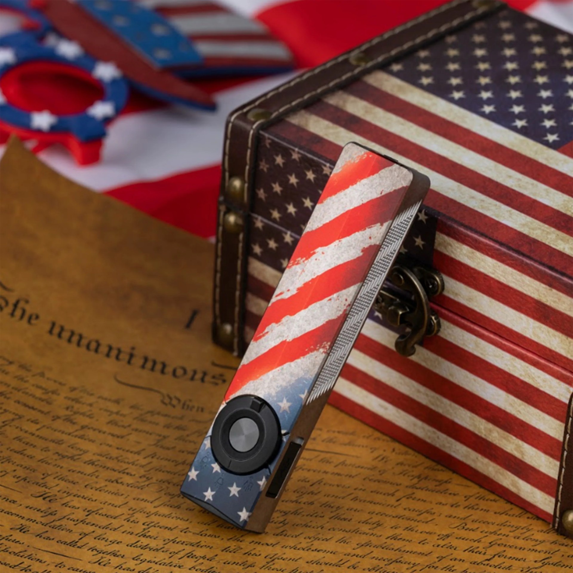 Electronic device with American flag design resting on an old document and a matching box.