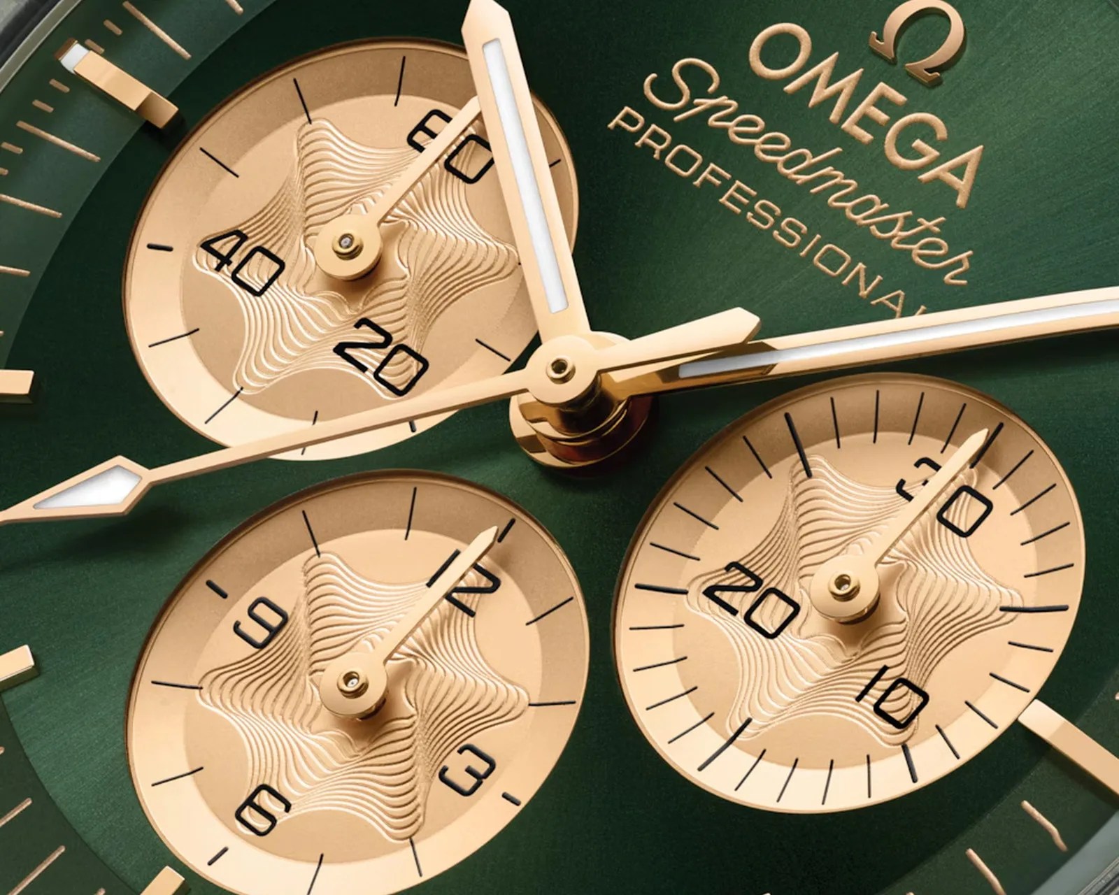 Close-up of an Omega Speedmaster Professional watch face with green background and gold subdials and hands.