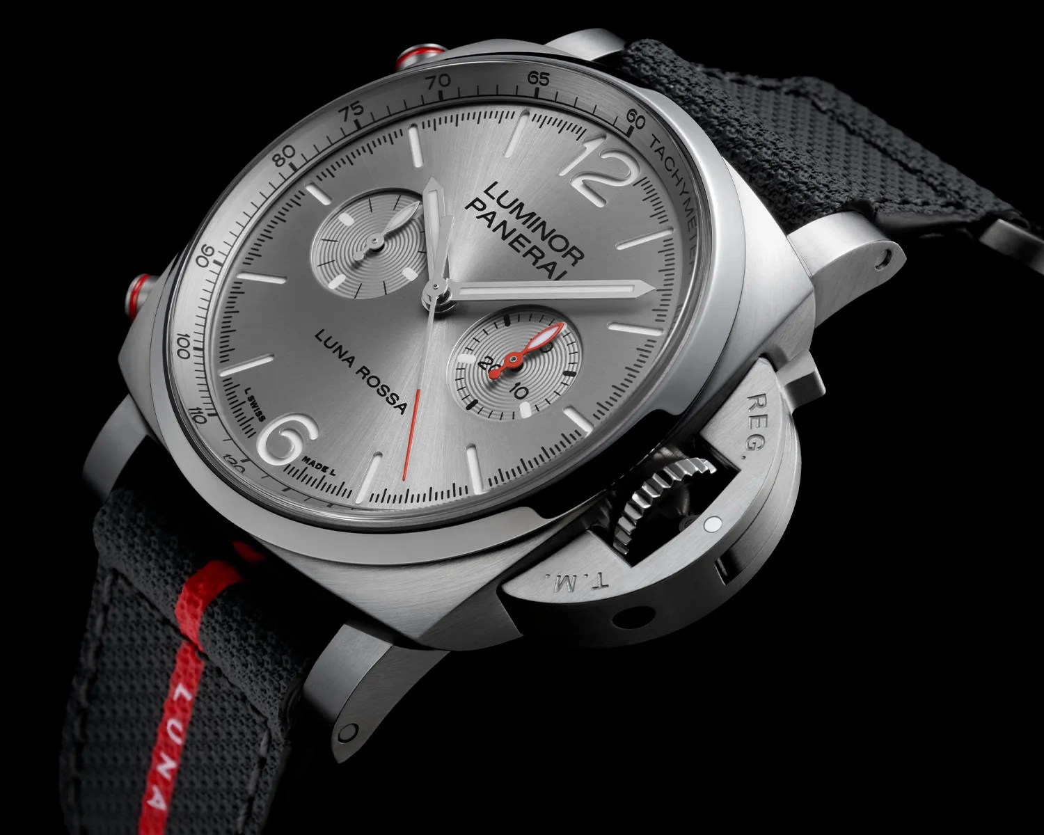 Silver Panerai Luminor Luna Rossa chronograph watch with black fabric strap and red accents on a black background.