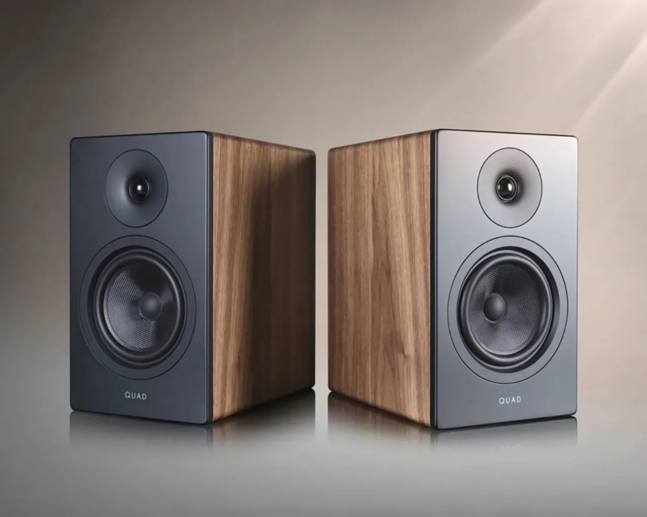 Pair of rectangular bookshelf speakers with black front panels and wooden side panels, labeled "QUAD.