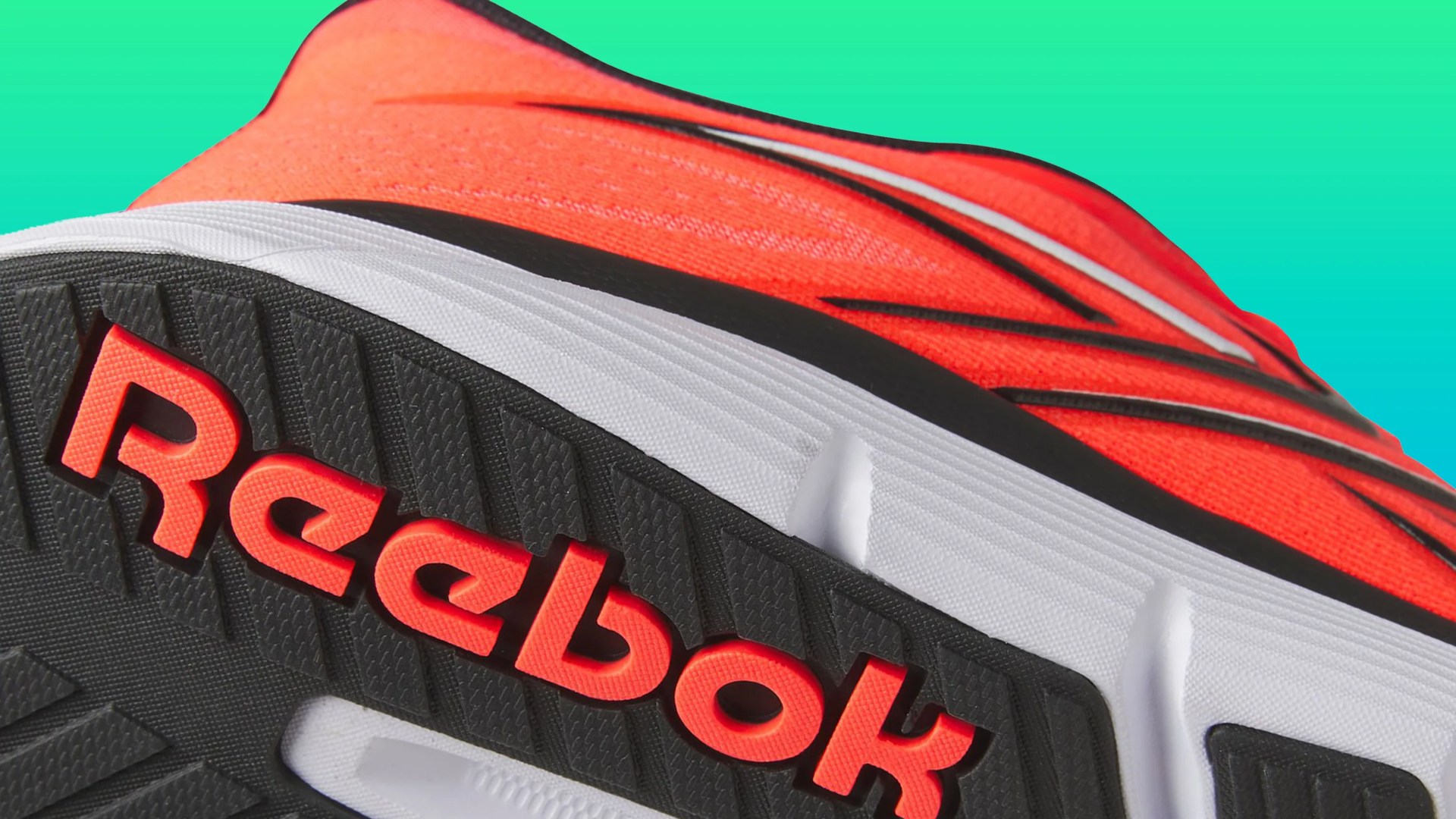 Close-up of a bright orange Reebok shoe sole with black and white tread details.