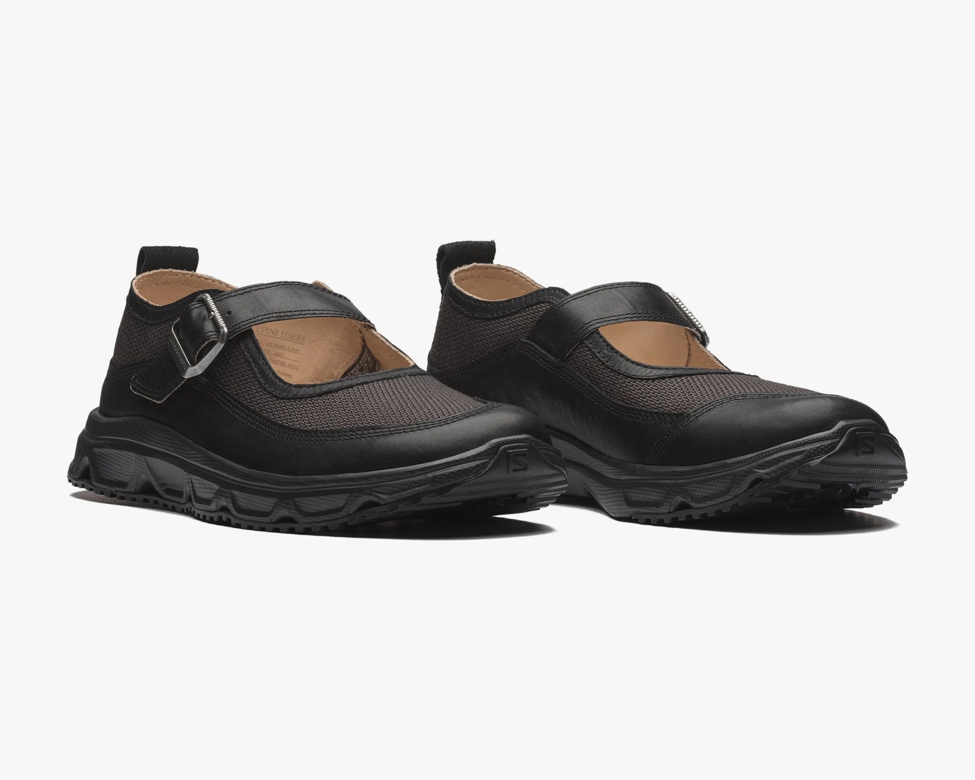 Pair of black Mary Jane style shoes with mesh and leather upper, adjustable strap, and thick rubber sole.